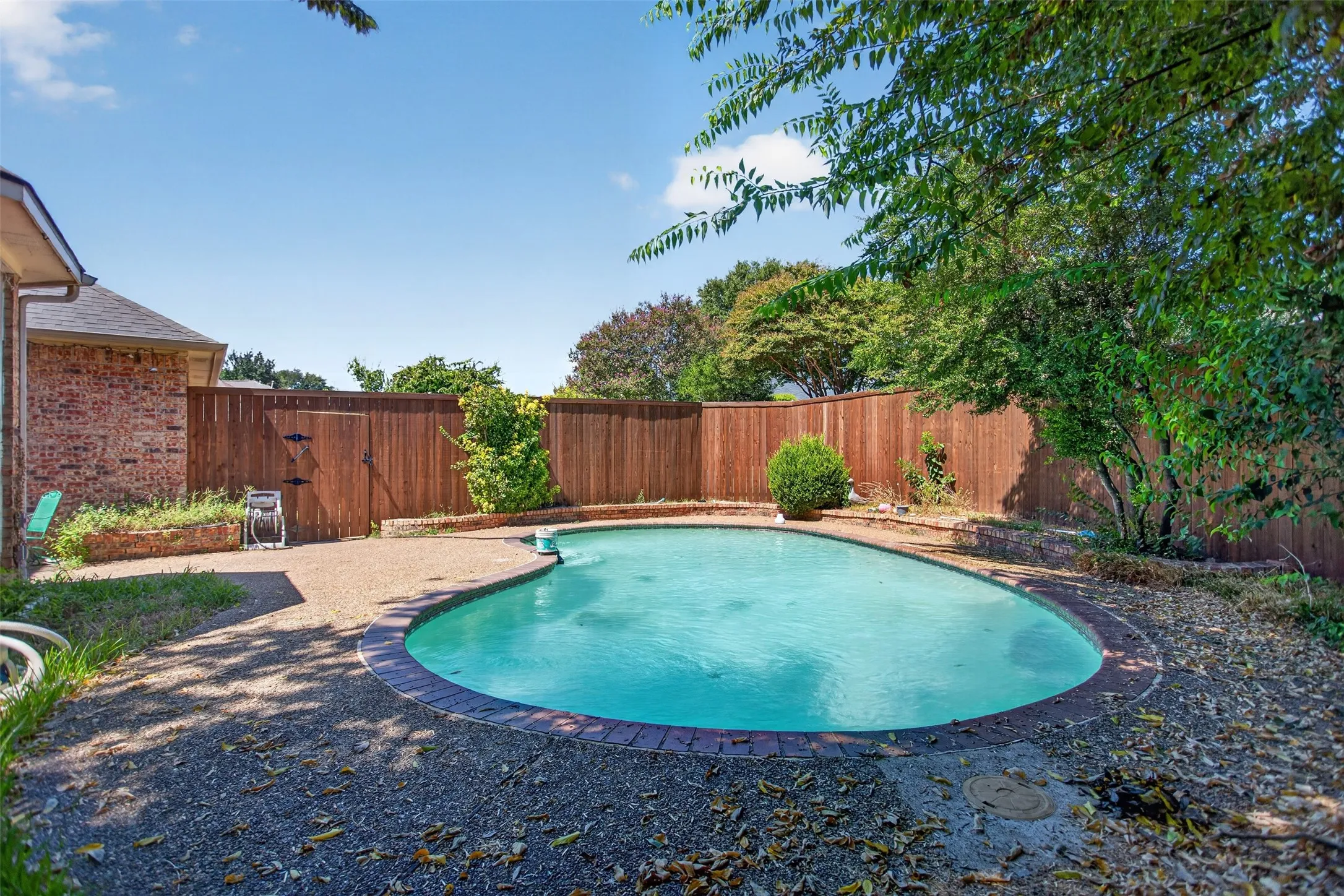 Private backyard with an inground pool, surrounded by a wood fence, and mature trees