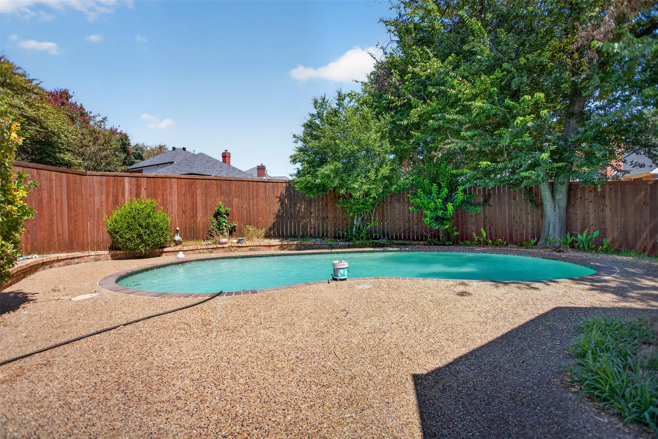 Oval-shaped swimming pool with a surrounding aggregate concrete deck