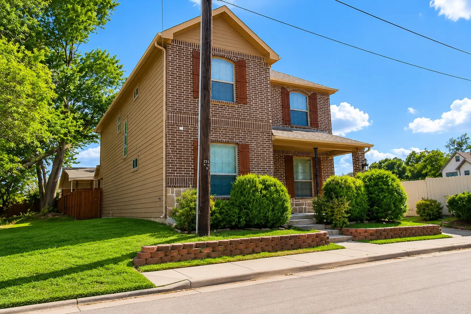 Brick and siding exterior with a covered front porch, arched windows, and decorative shutters