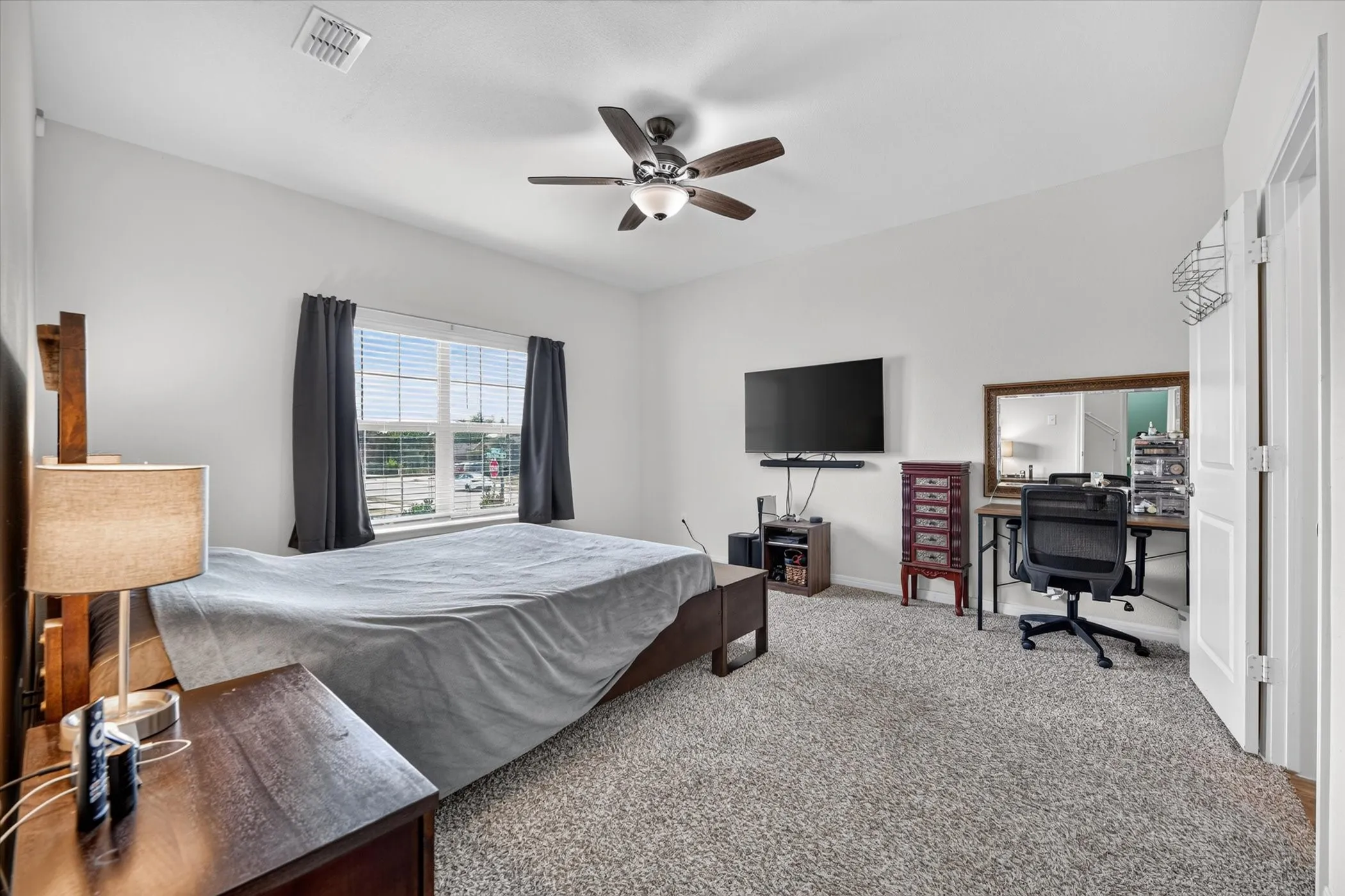 Neutral tone walls with textured carpeting, featuring a ceiling fan with integrated lighting