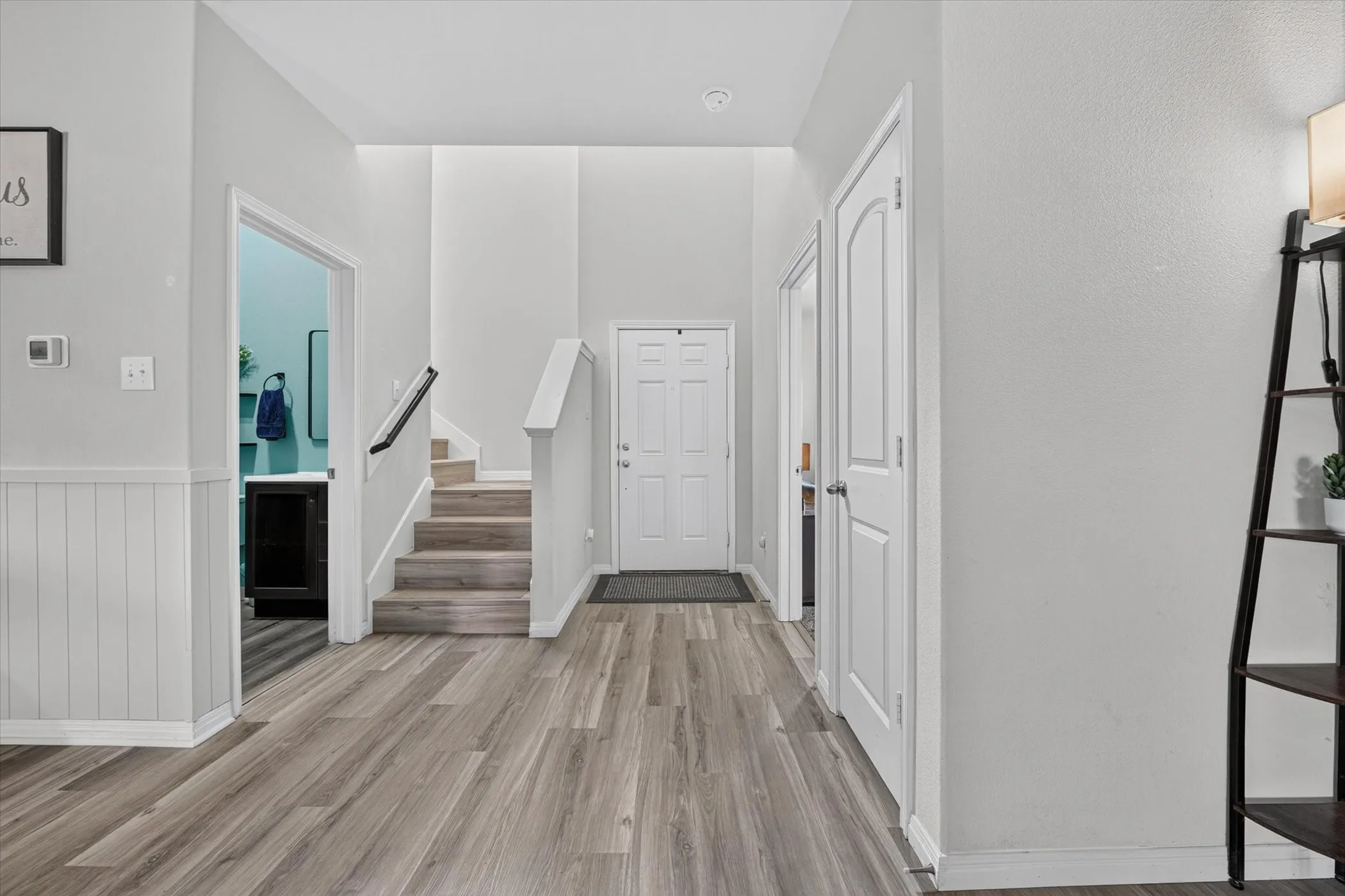 Entryway featuring wood-finish flooring, wainscoting, a staircase with wood-finish treads, and a built-in vanity with a vessel sink