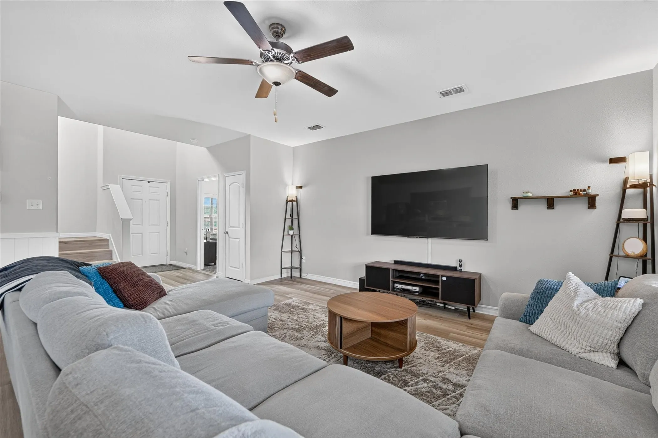 Expansive living space featuring wood-finish flooring, a ceiling fan, and light gray walls