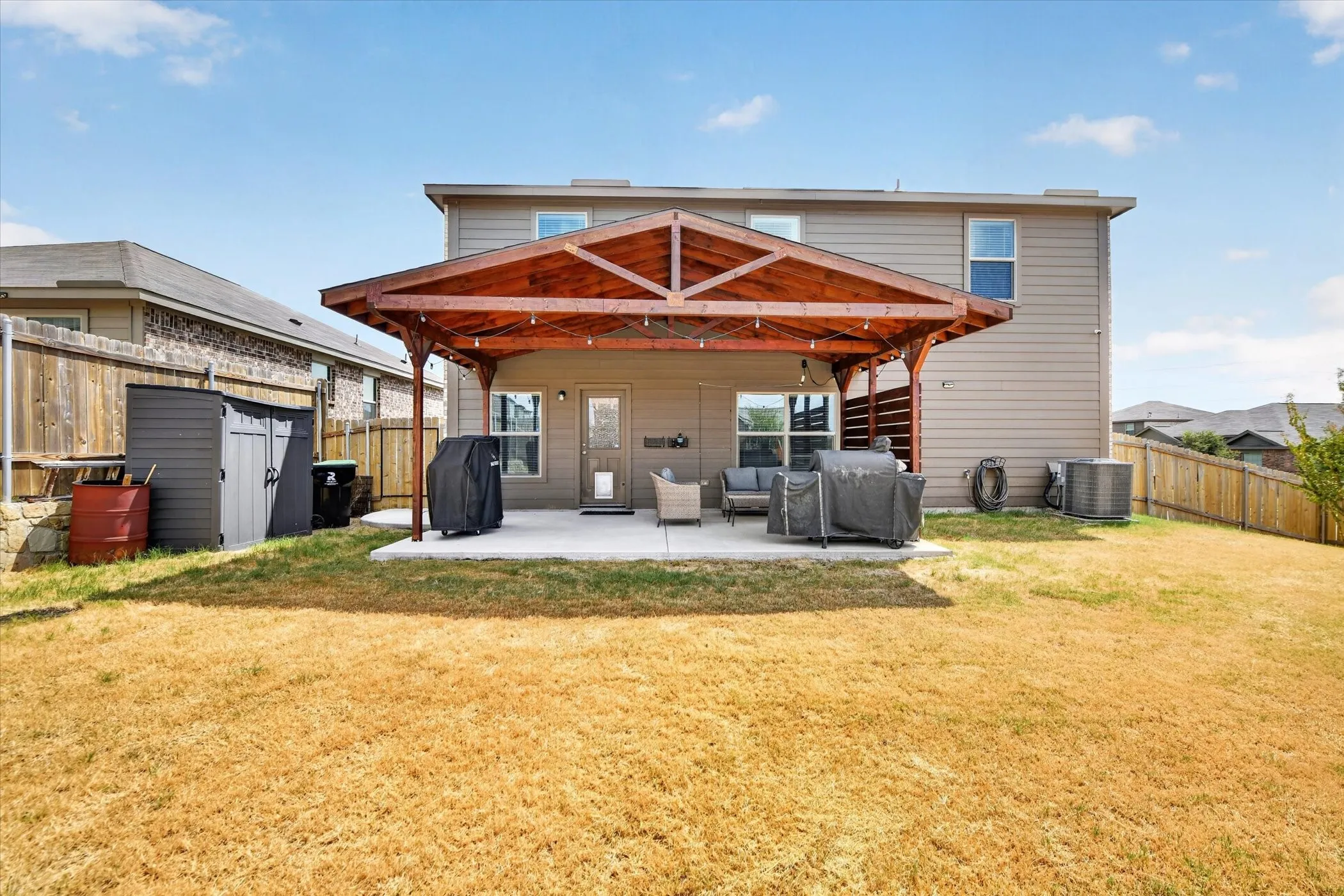 Expansive concrete patio with a wood-framed pergola