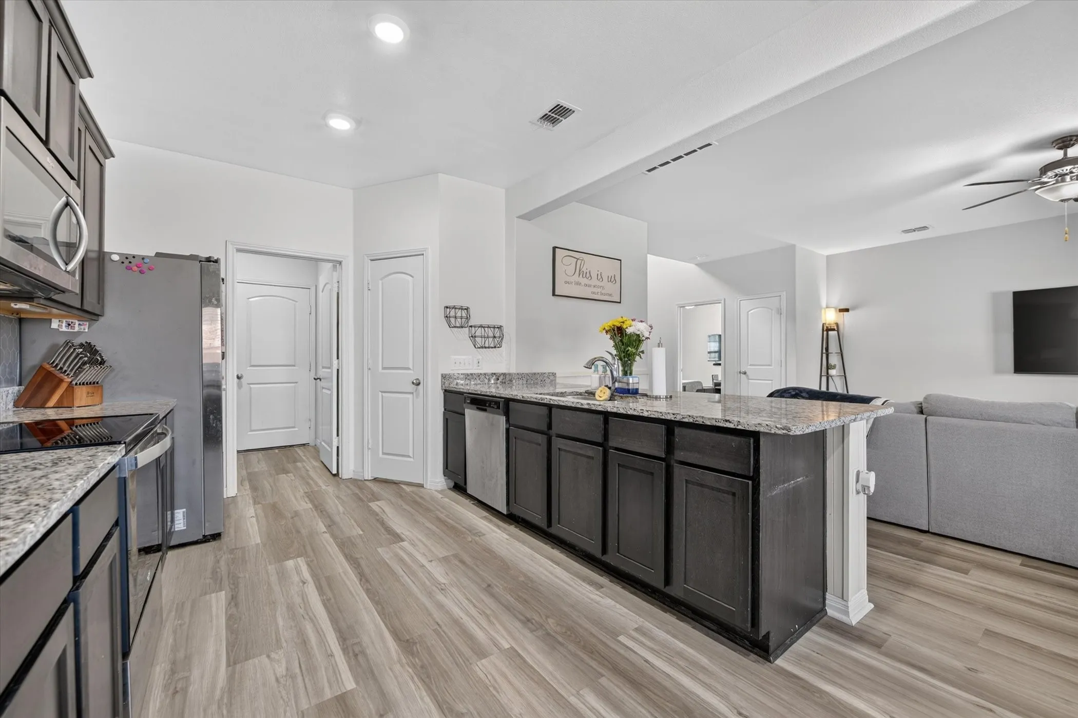 Kitchen featuring an island with stone countertops, dark wood cabinetry, stainless steel appliances, and wood-finish flooring