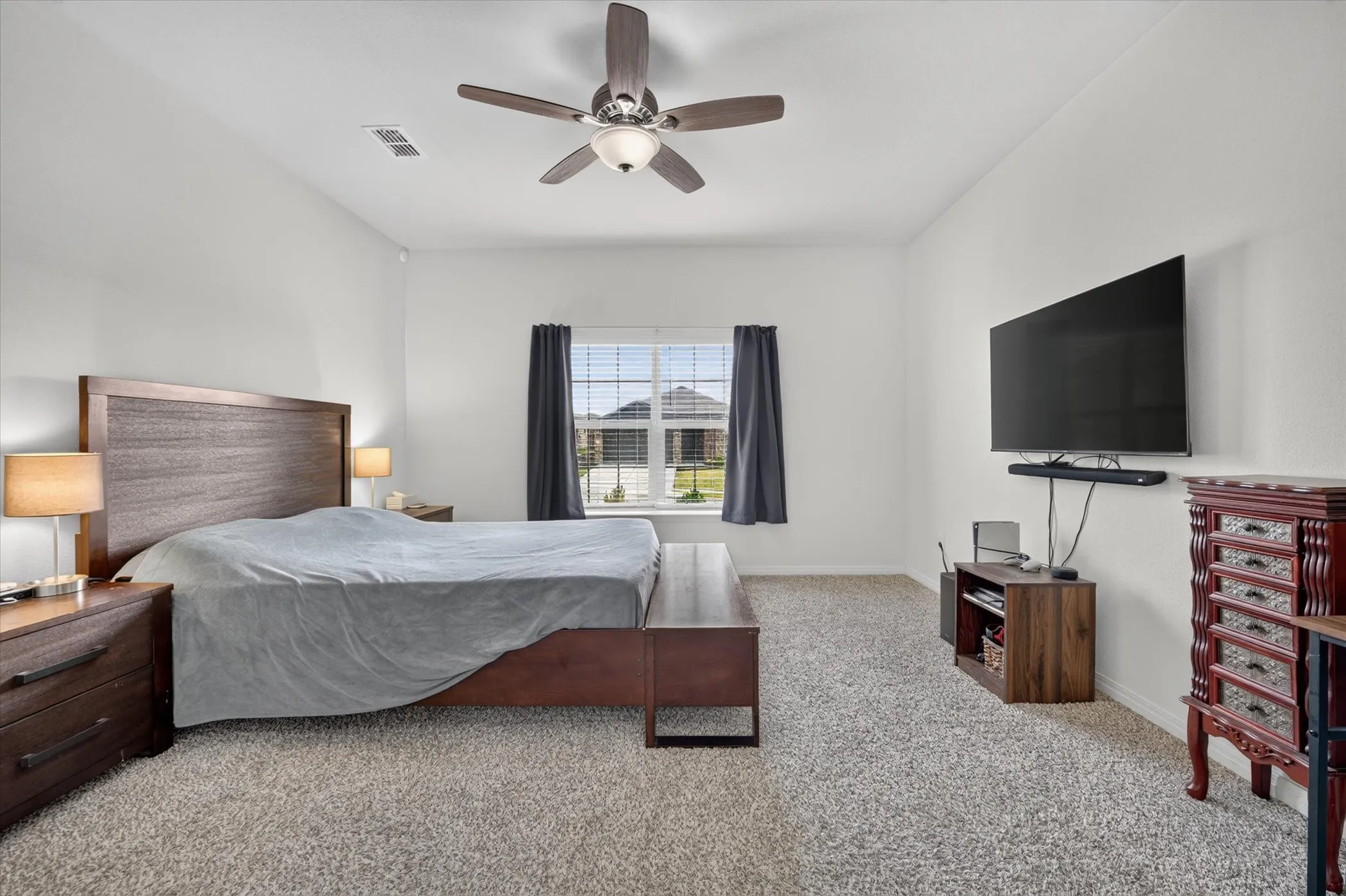 Spacious room featuring carpeting, a ceiling fan, and a window with blinds and drapes