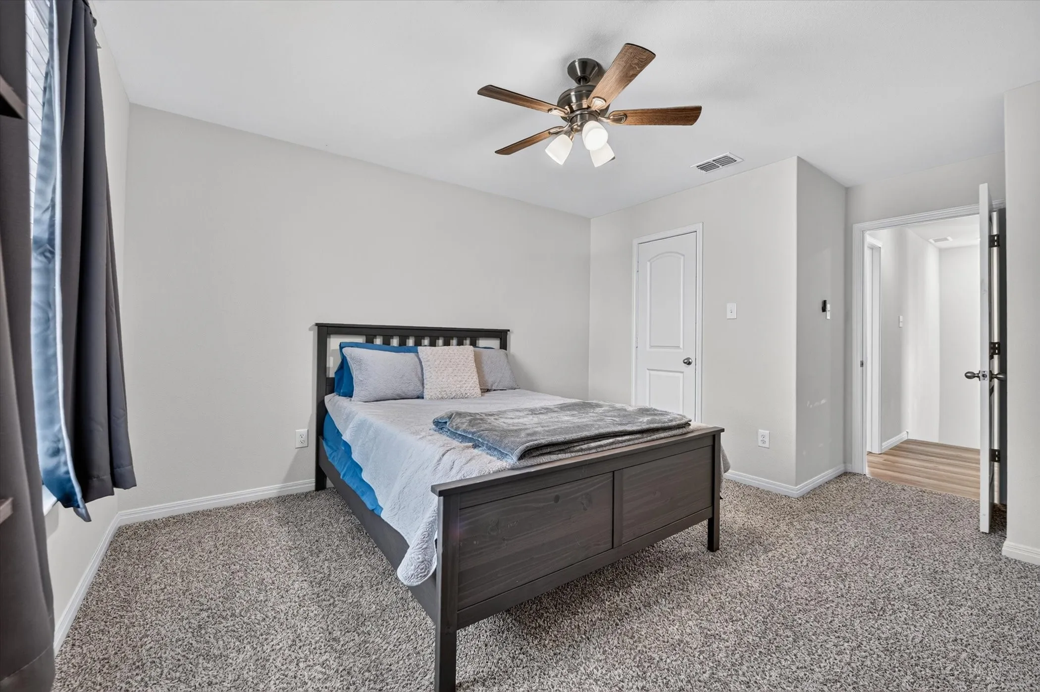 Carpeted room featuring a ceiling fan with light fixture and a white paneled door