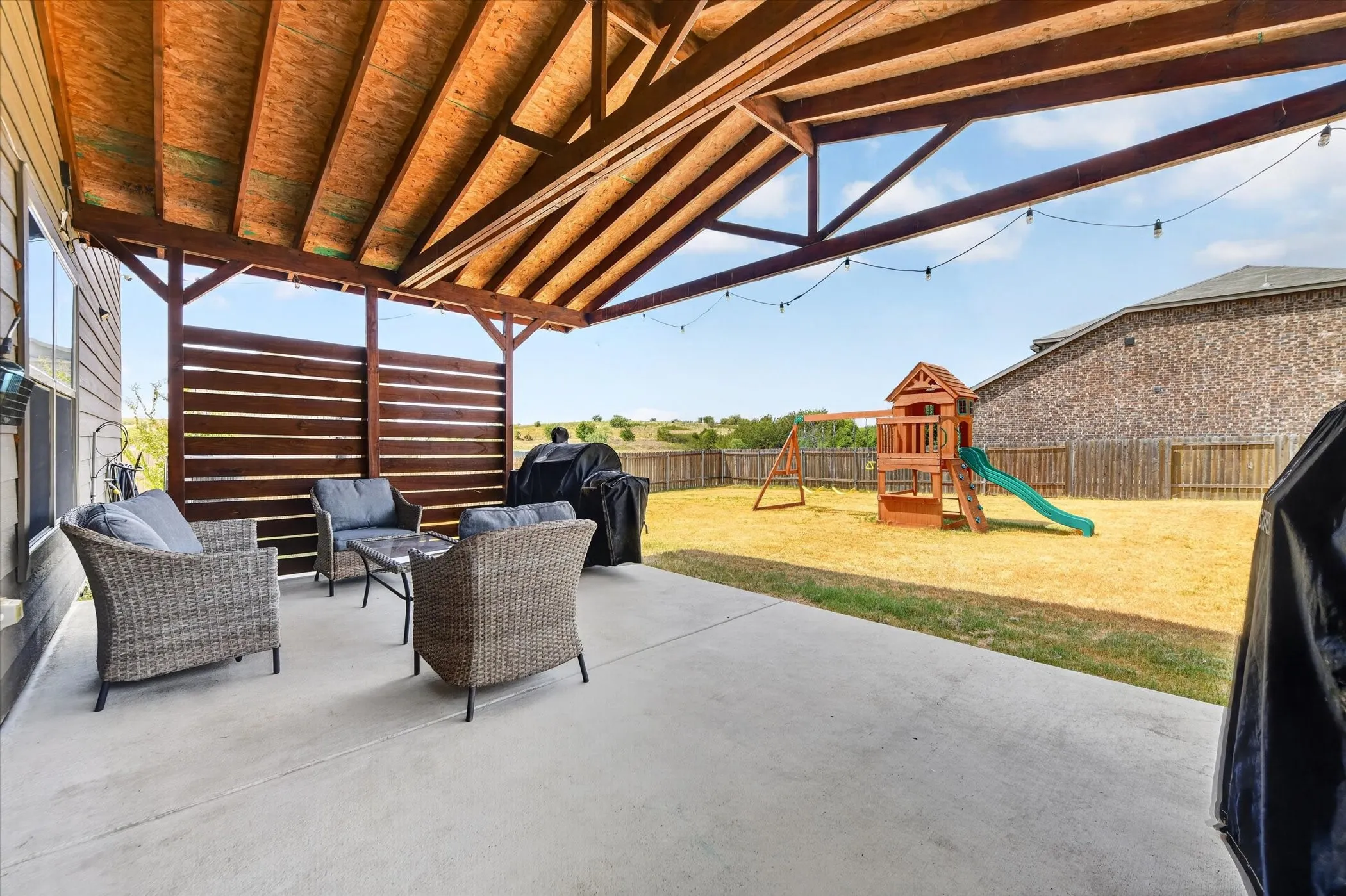 Expansive concrete patio with a wood-framed covered pergola