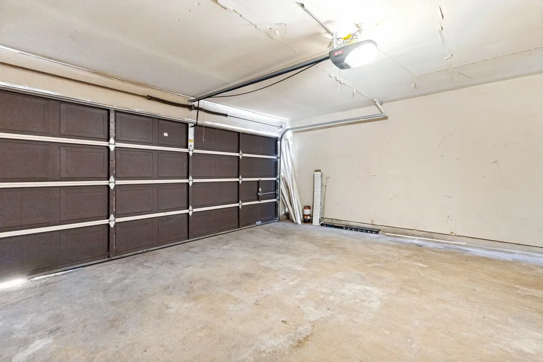 Attached garage with a panel-style door, concrete flooring, and ceiling-mounted lighting