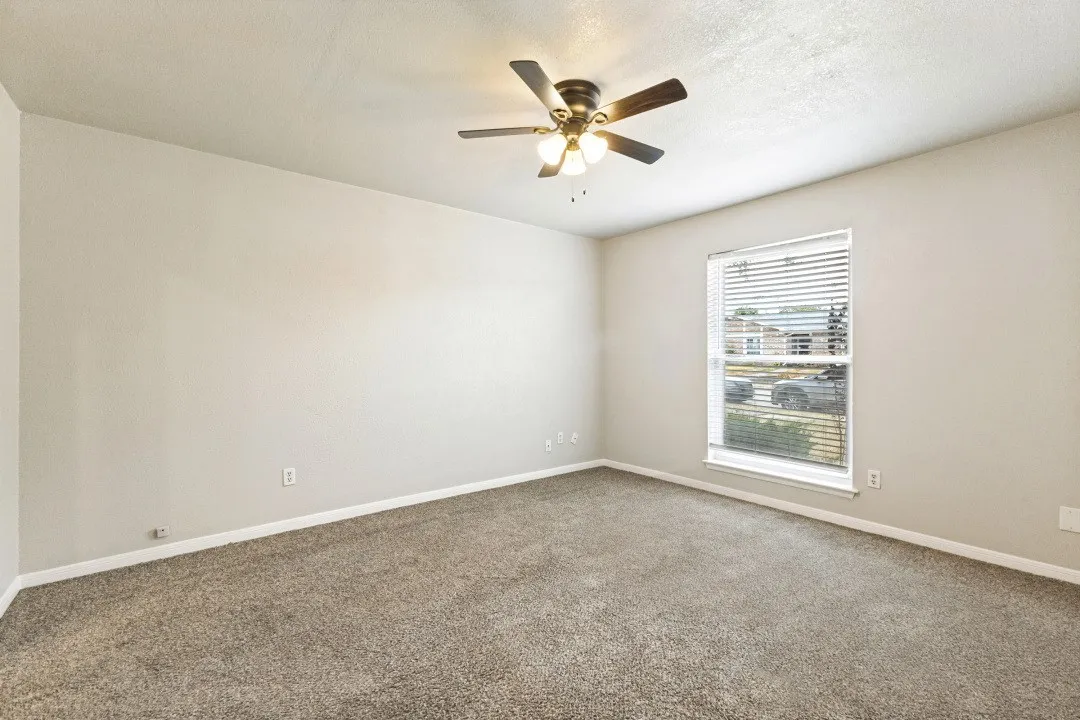 Neutral wall paint, carpet flooring, a ceiling fan with integrated lighting, and a window with horizontal blinds
