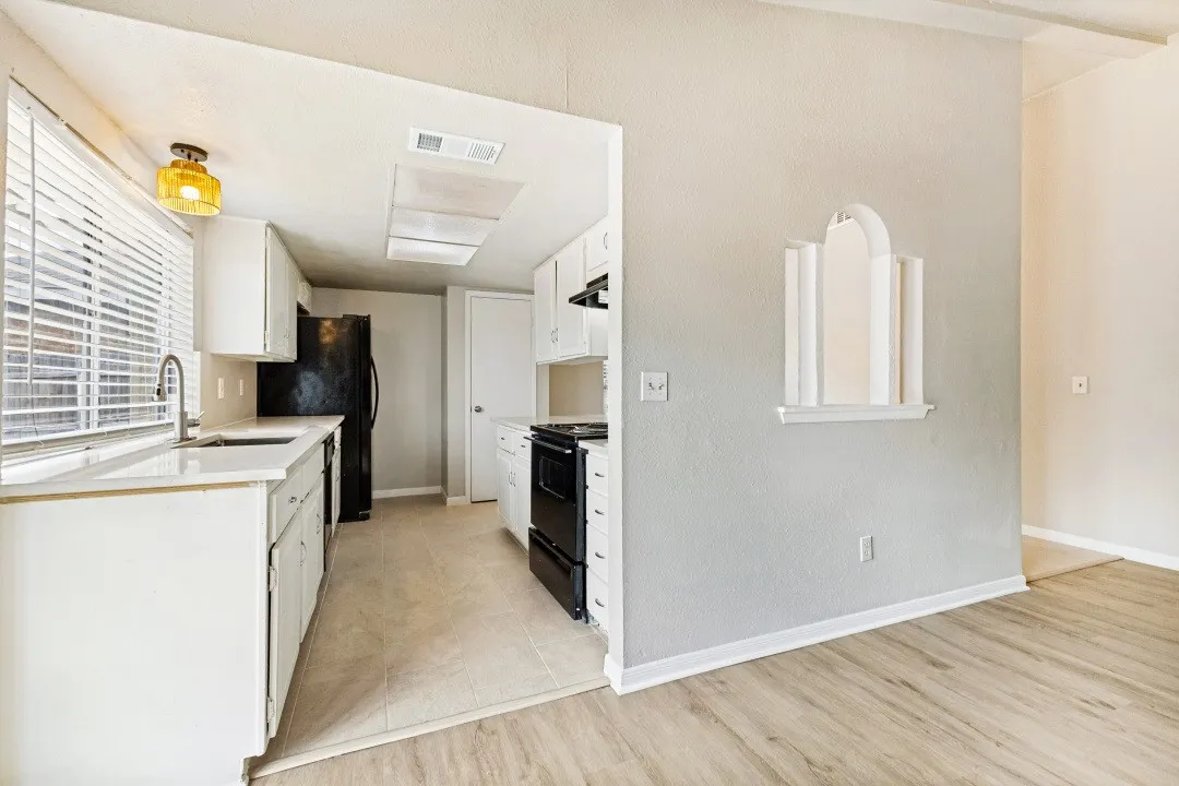 Kitchen with white cabinetry, light countertops, and a window with blinds