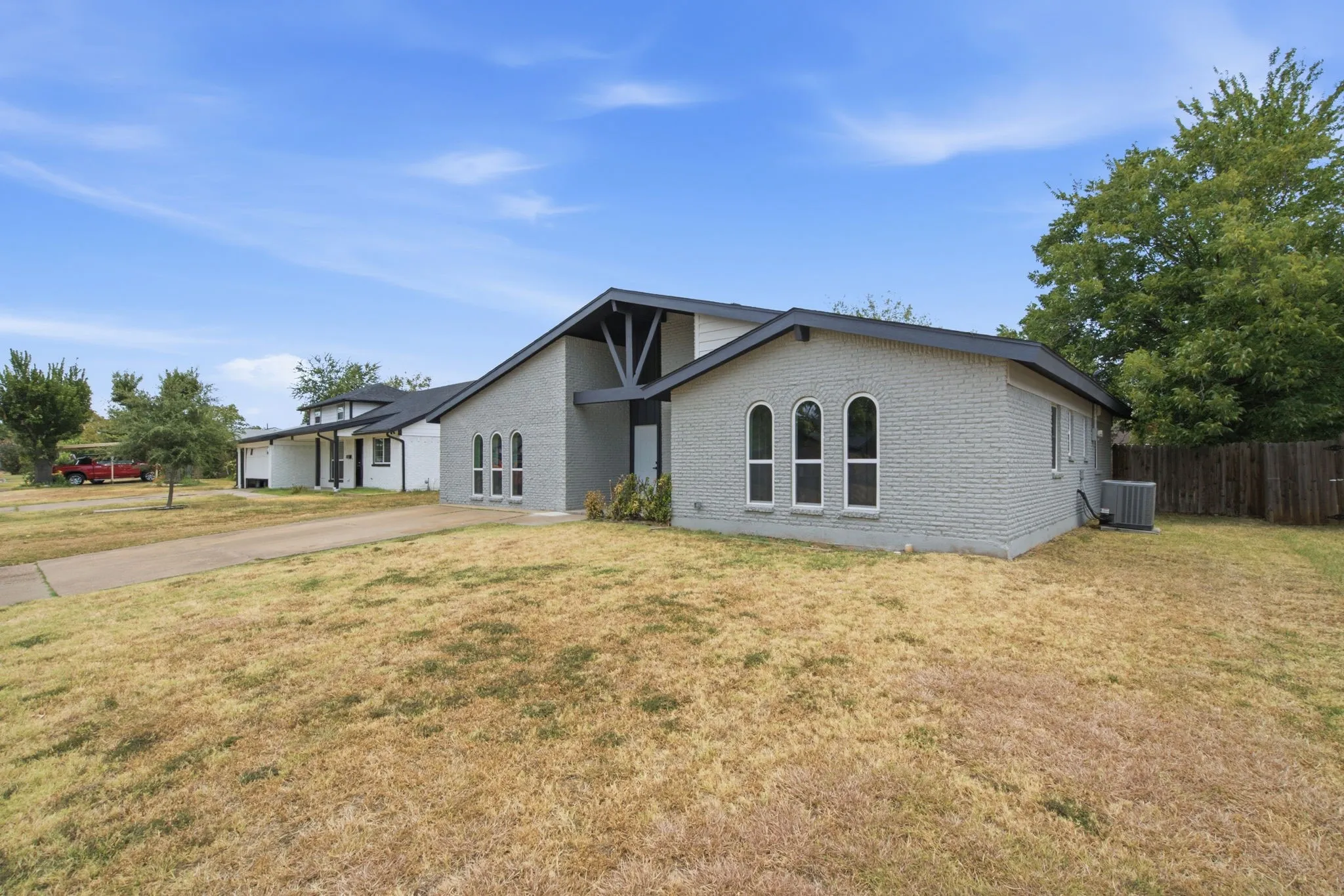 Light gray painted brick exterior with a black trim roof and arched windows