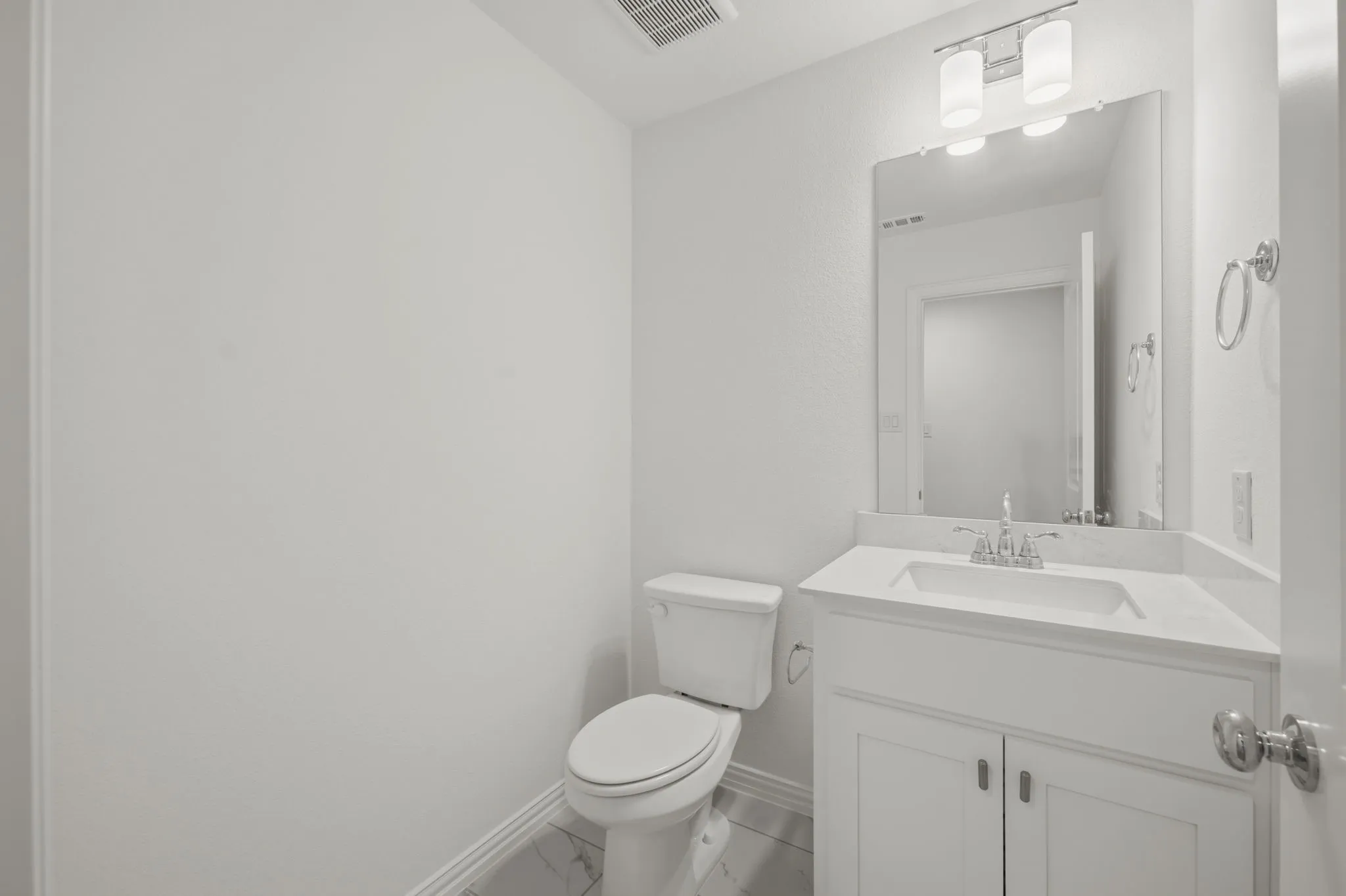 Vanity with an integrated sink, polished chrome faucet, and stone countertop