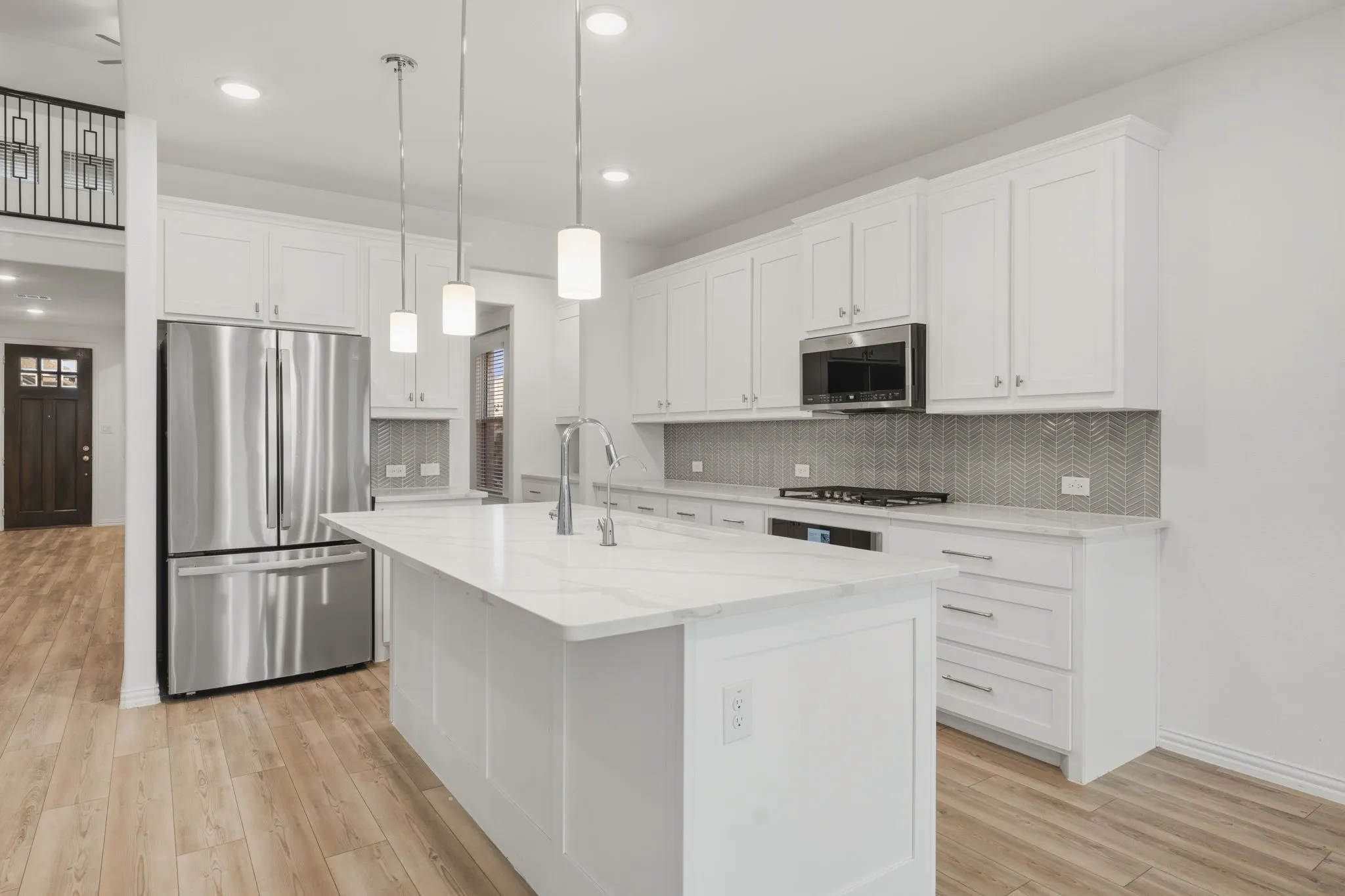 Kitchen featuring an expansive island with a polished countertop, stainless steel appliances, abundant white cabinetry, a tiled backsplash, and wood-finish flooring