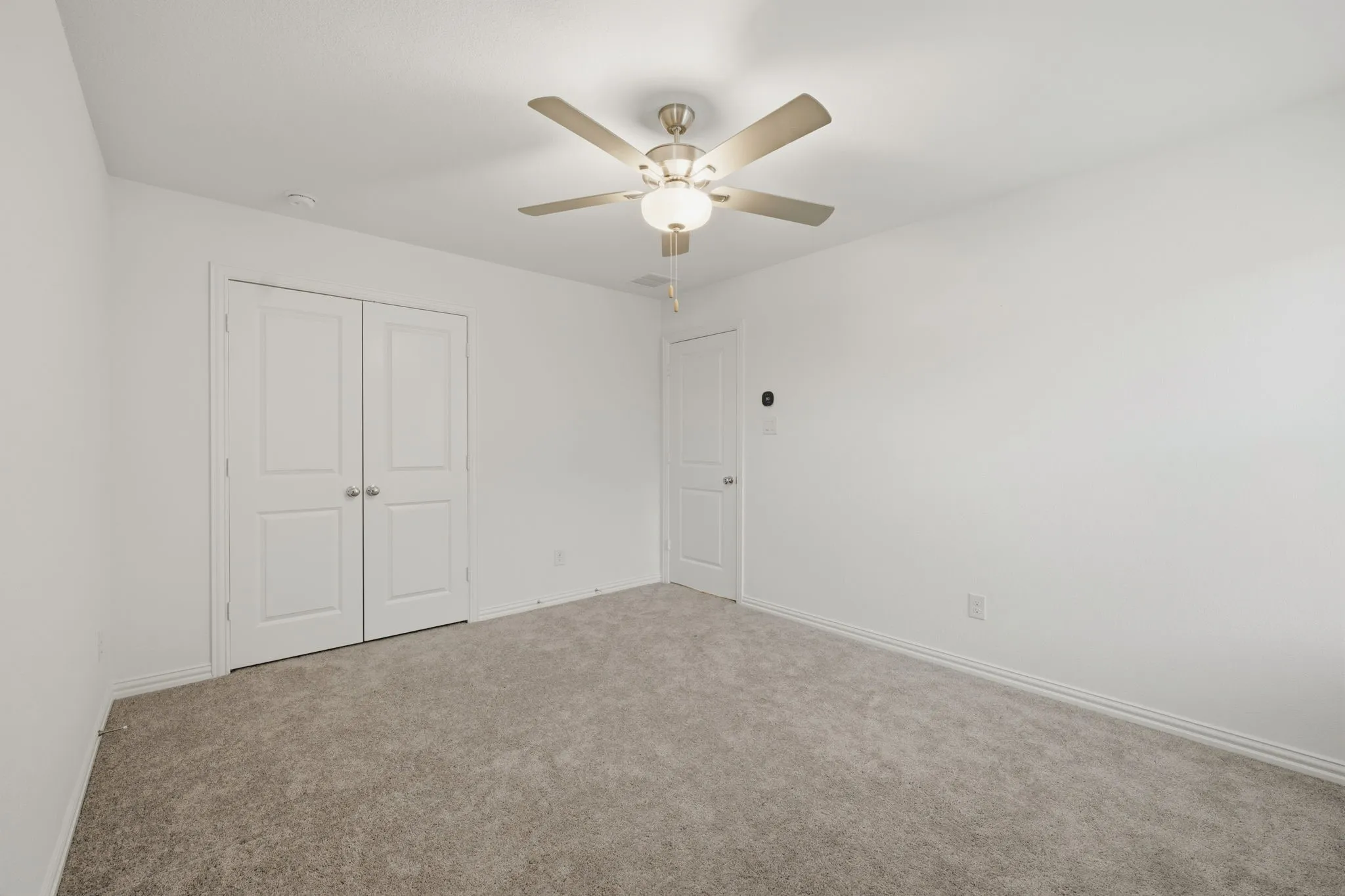 Plush carpet flooring, white walls, and a ceiling fan with integrated lighting