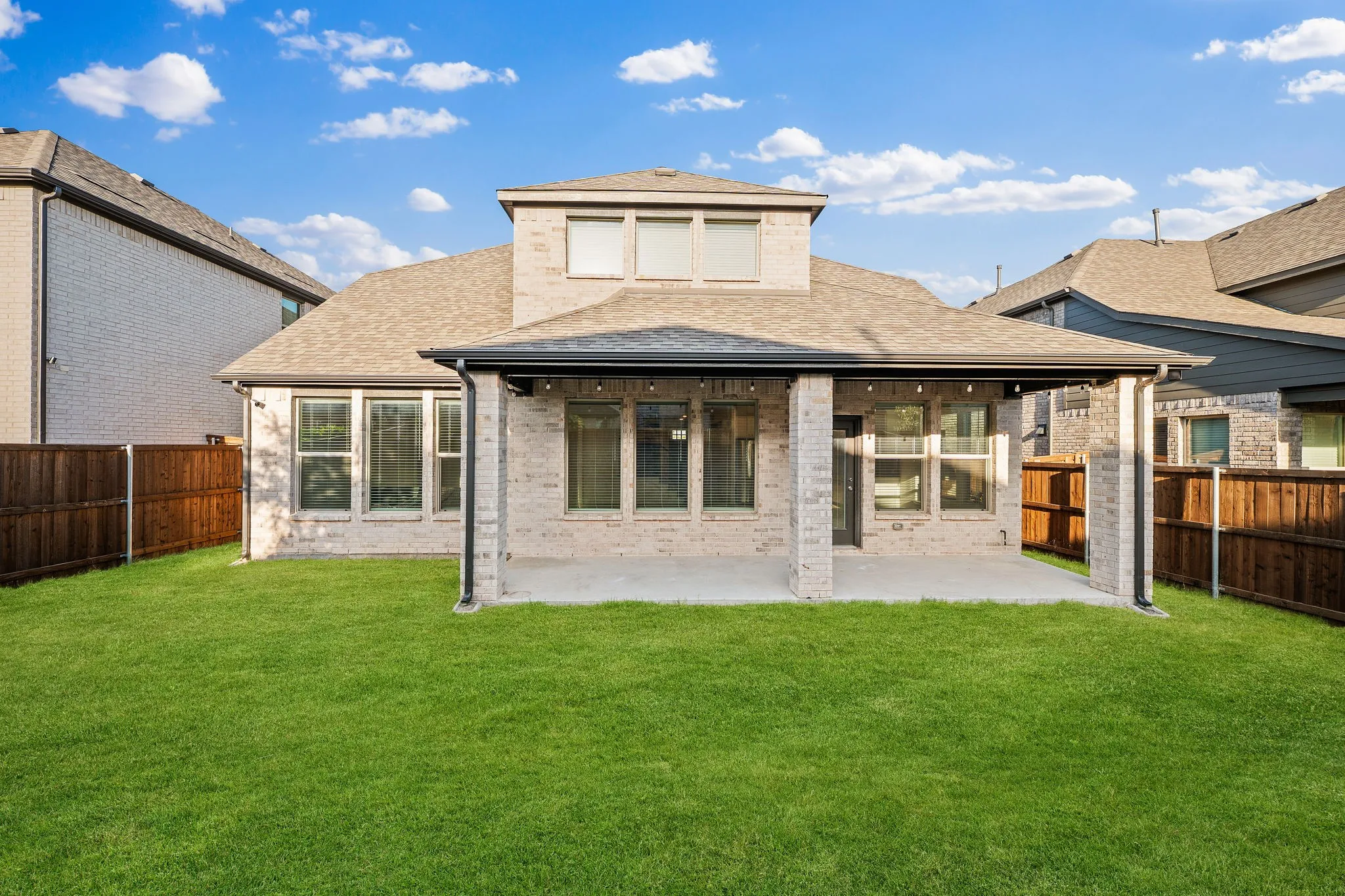 Spacious backyard featuring a covered patio, expansive lawn, and privacy fencing
