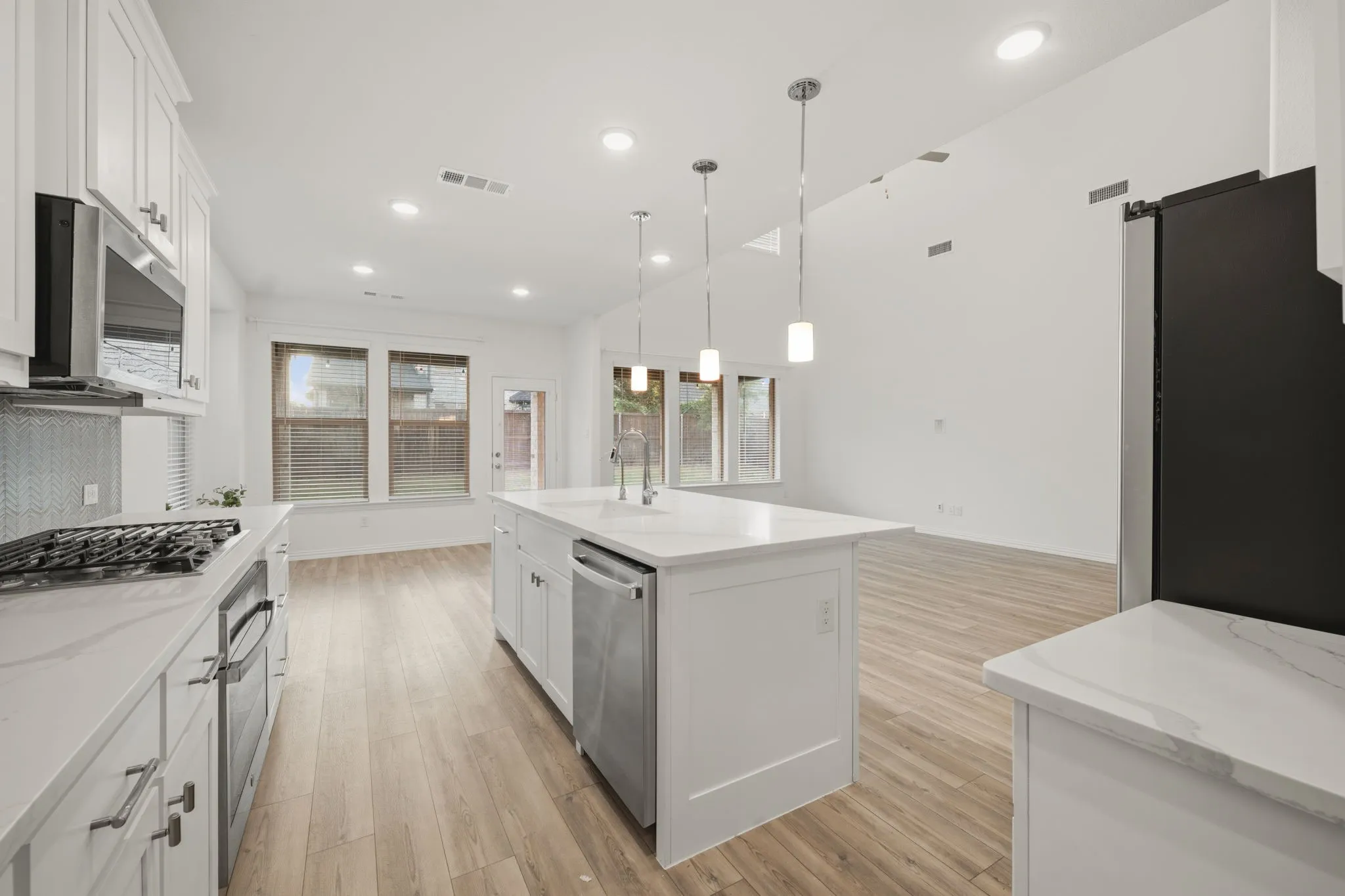 Gourmet kitchen with white cabinetry, stainless steel appliances, a center island with pendant lighting, and stone countertops