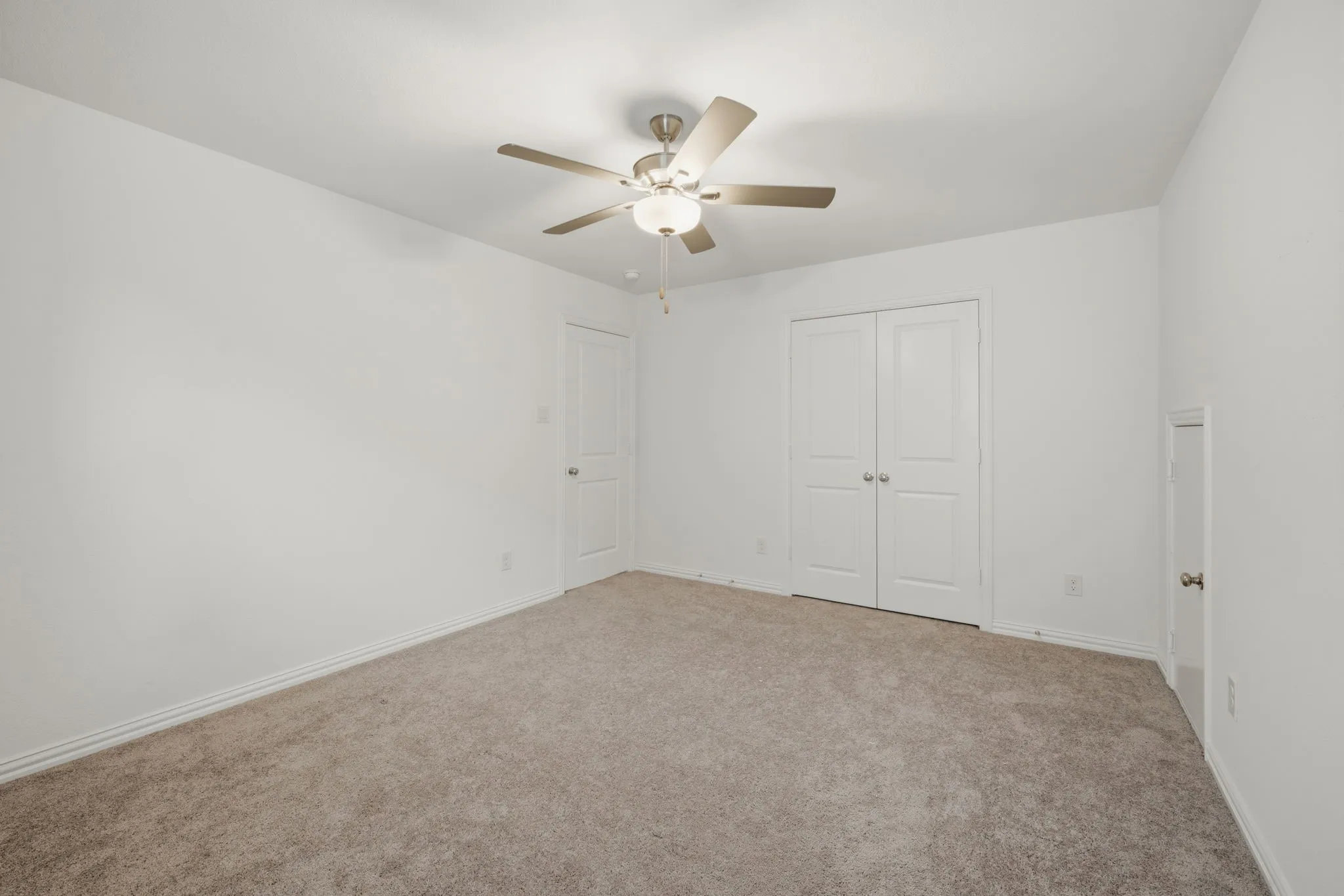 Neutral wall color, carpet flooring, ceiling fan with light fixture, and white bi-fold closet doors