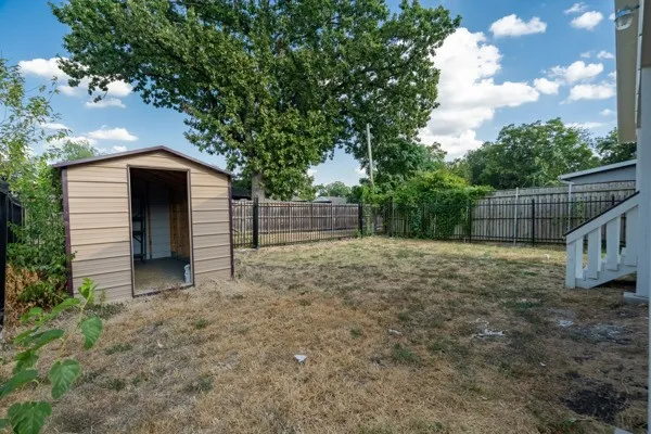 Spacious backyard featuring a metal storage shed, wood fencing, and a black metal fence section
