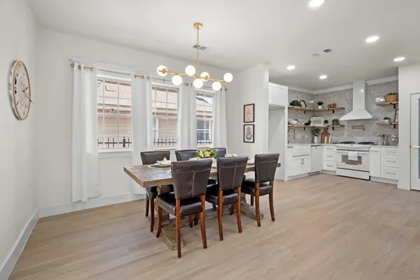 Open-concept living space with light wood-finish flooring, white walls, and recessed lighting