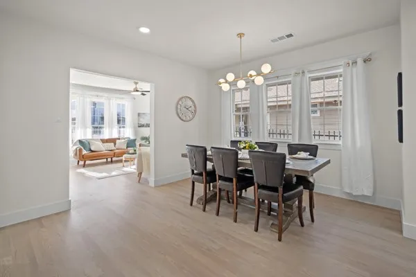 Recessed lighting, wood-finish flooring, white walls, and a modern linear chandelier