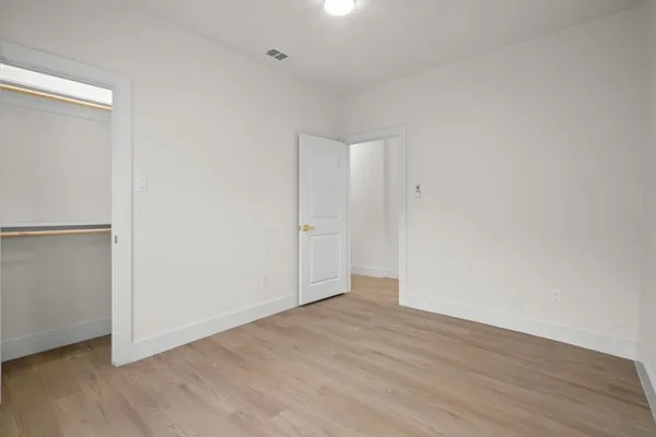Wood-finish flooring, white painted walls, recessed closet, and white interior doors