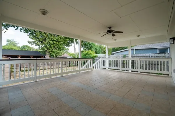 Expansive covered deck featuring tile flooring, white railing, and a ceiling fan