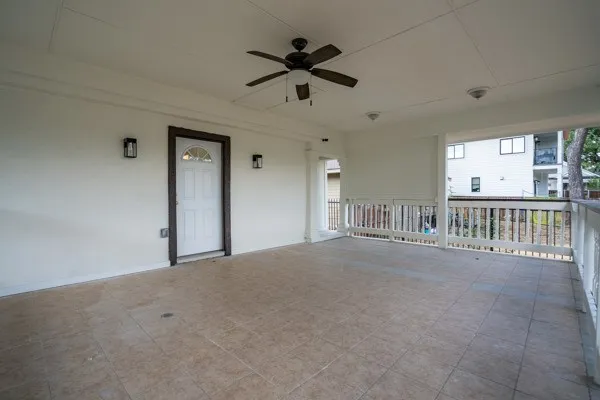 Expansive covered porch featuring tile flooring, a ceiling fan, and decorative wall sconces