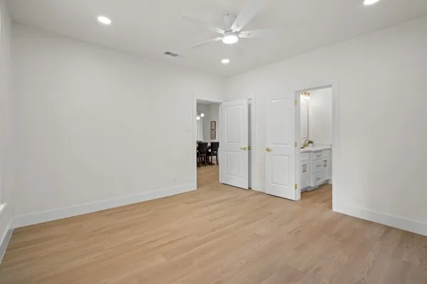 Recessed lighting, ceiling fan, wood-finish flooring, white double doors, and a vanity with a rectangular sink