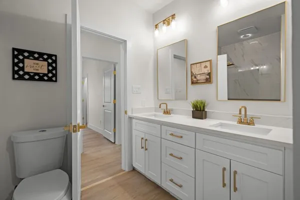 Dual vanity with white shaker-style cabinetry, gold-finish hardware, and integrated sinks