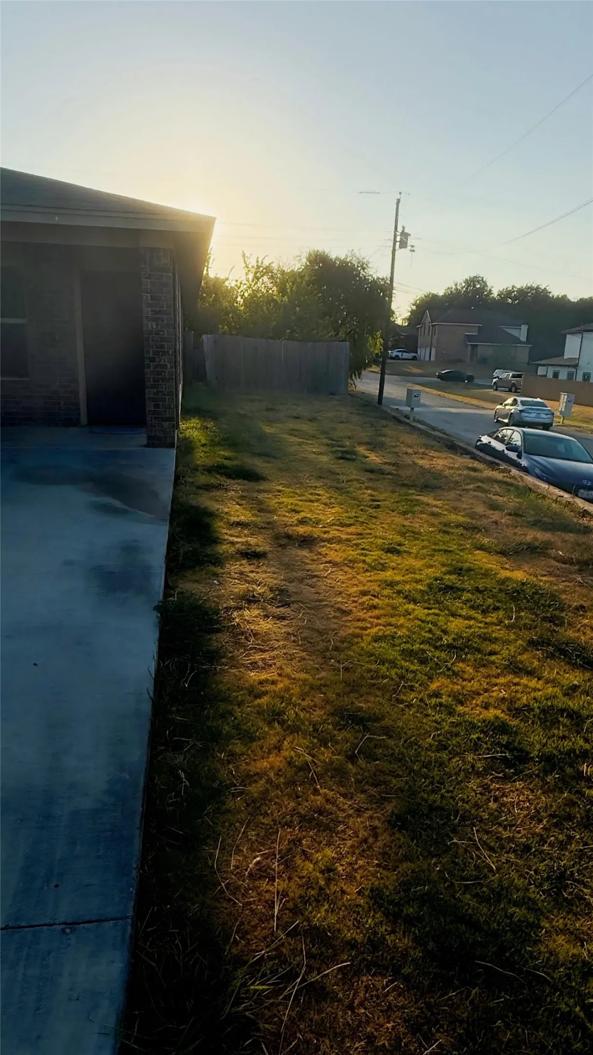 Concrete driveway with an attached garage, a spacious lawn, and a wood privacy fence
