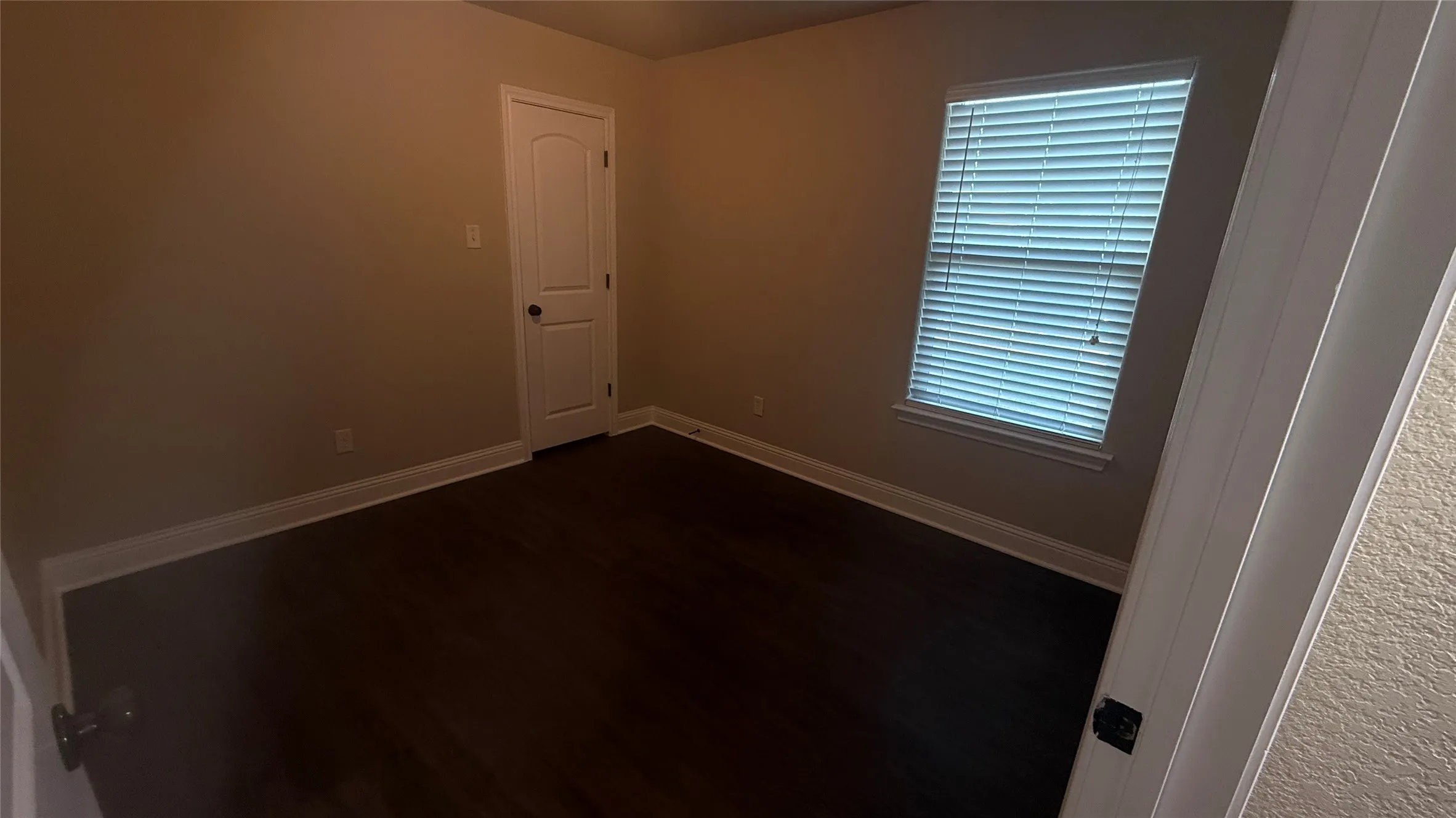 Wood-finish flooring, neutral wall tones, white trim, and a window with blinds