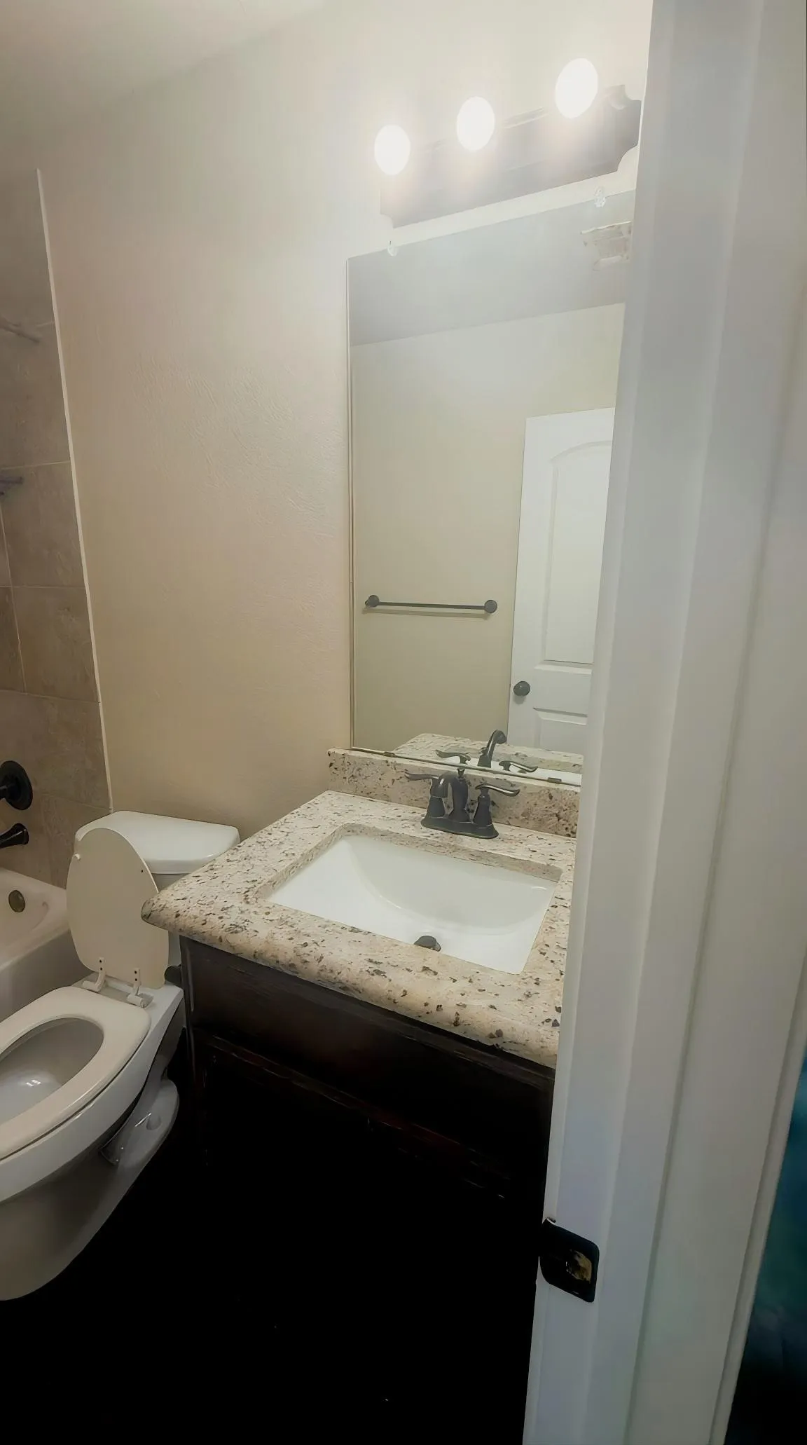 Bathroom featuring a vanity with a light-toned countertop, an integrated sink, dark wood-finish cabinetry, and a wall-mounted mirror