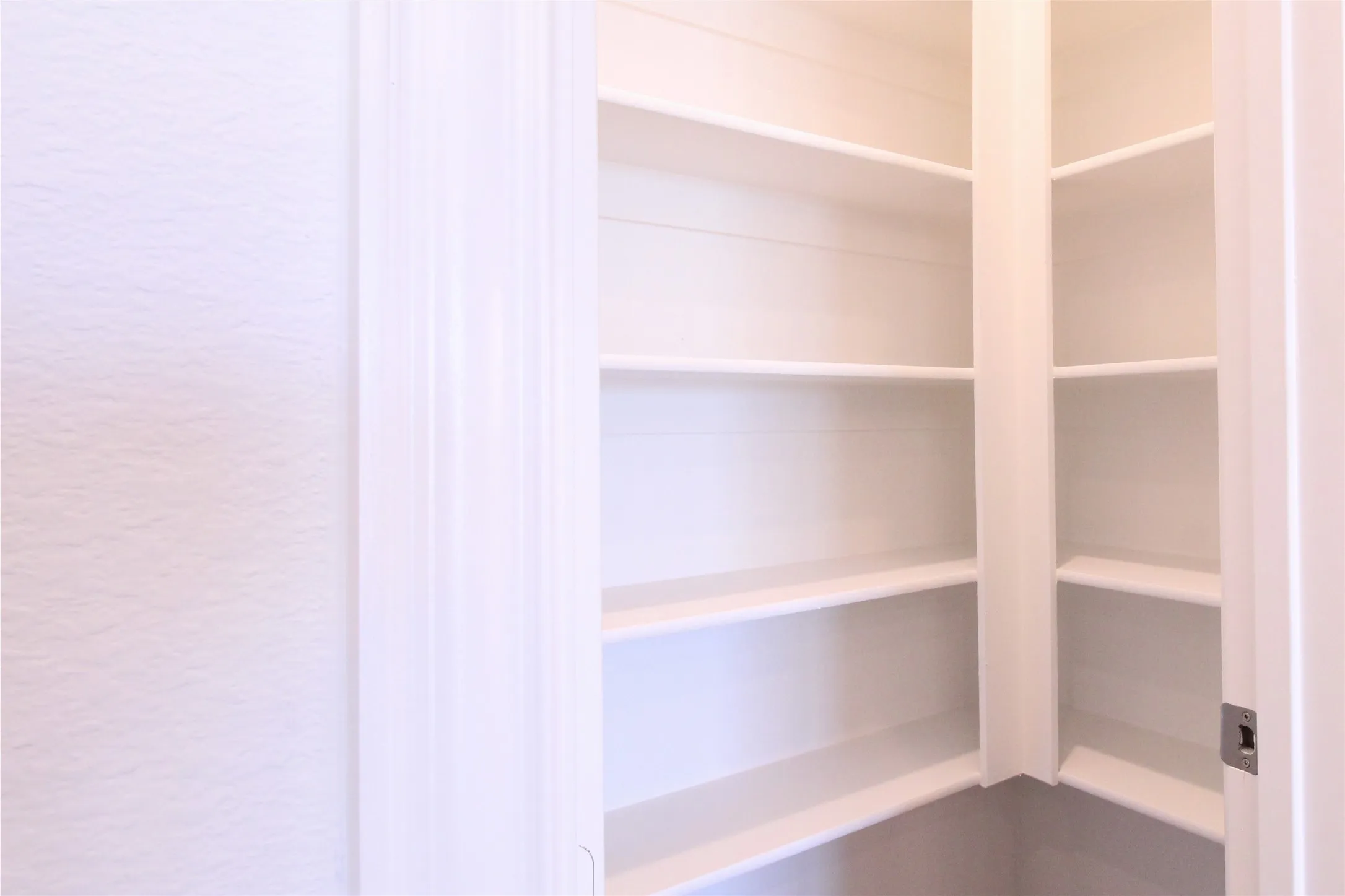 Built-in pantry shelving featuring painted white wood, multiple tiers, and a corner configuration