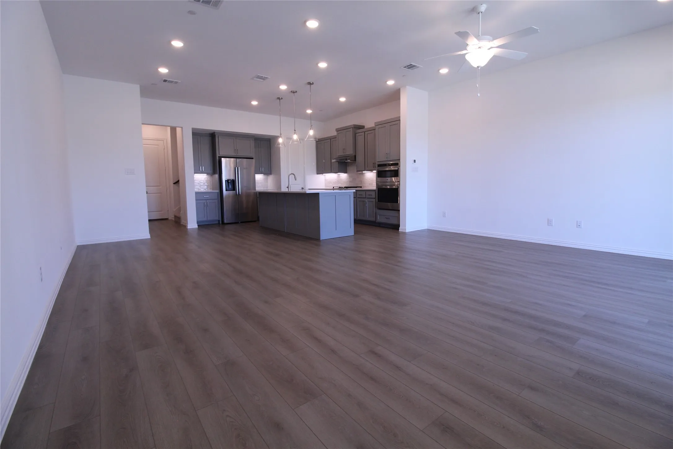 Spacious open-concept living area featuring wood-finish flooring, recessed lighting, and a ceiling fan