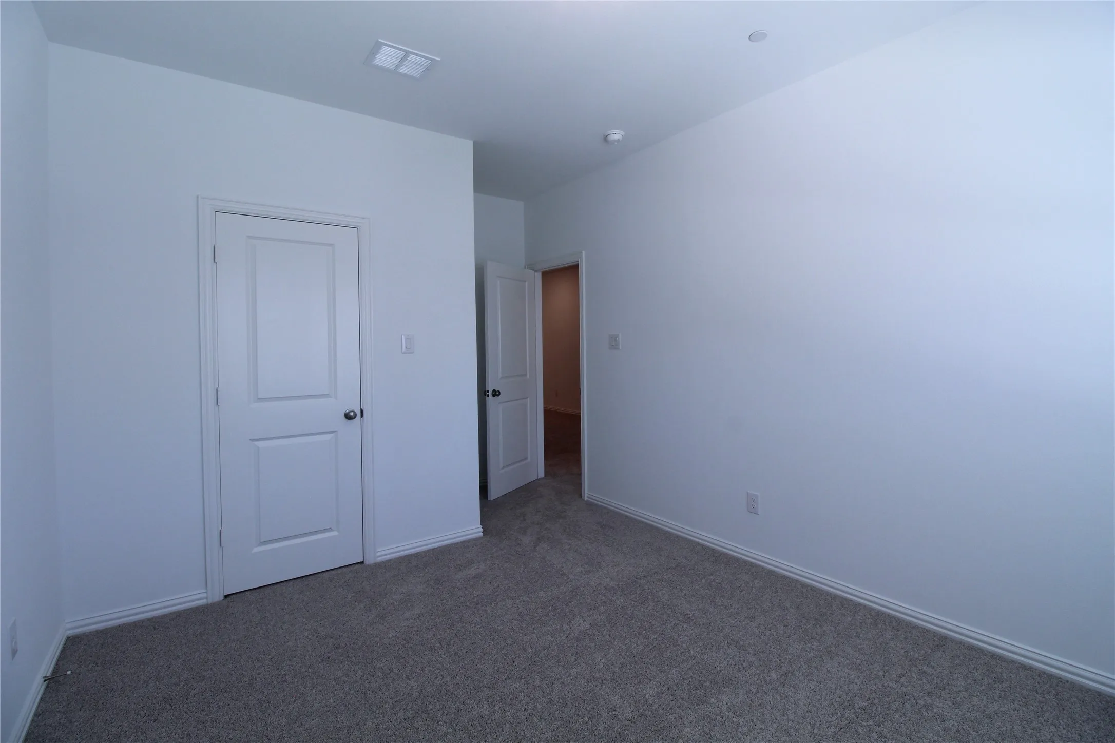 Neutral wall paint with gray carpet flooring and white baseboards