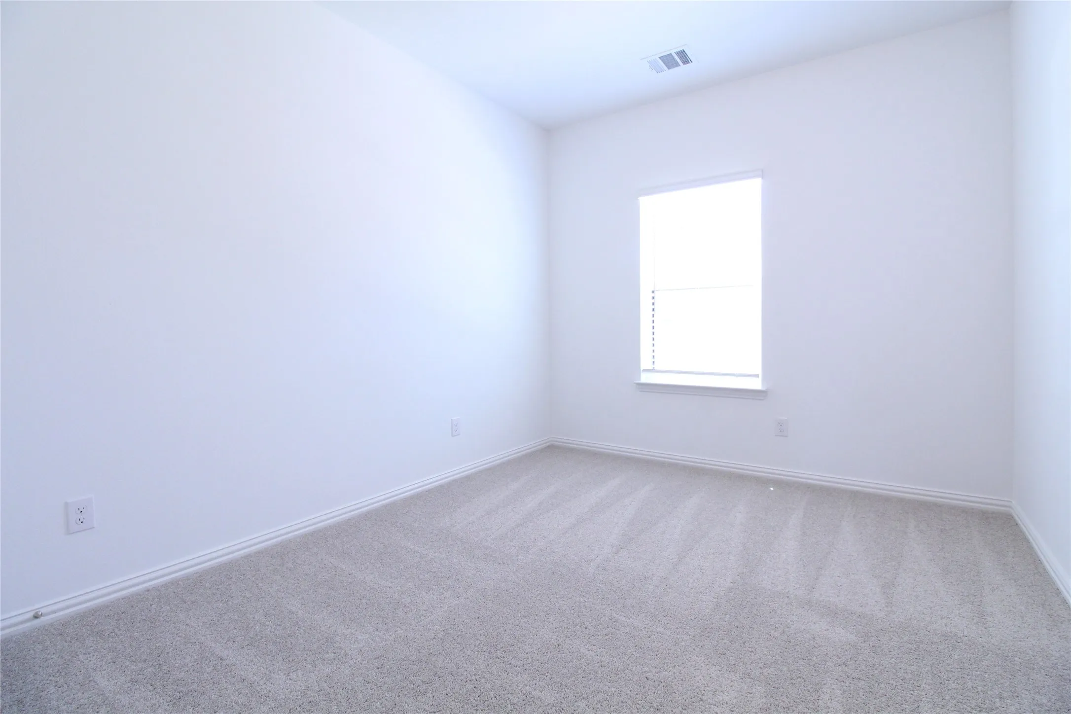 Room with light gray carpeting, a single window with horizontal blinds, white baseboard trim, and a ceiling vent