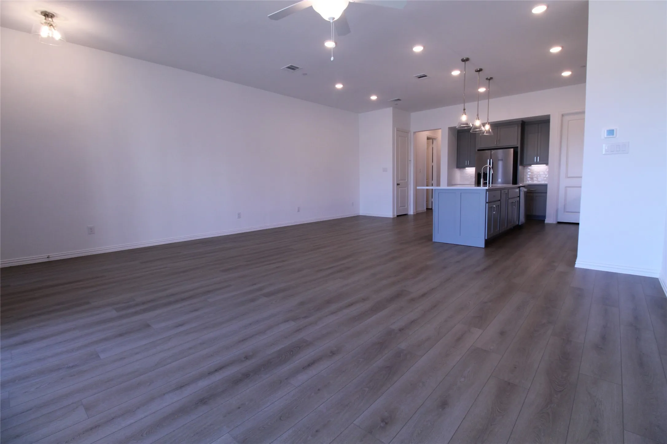 Spacious open-concept room featuring wood-finish flooring, recessed lighting, and a ceiling fan