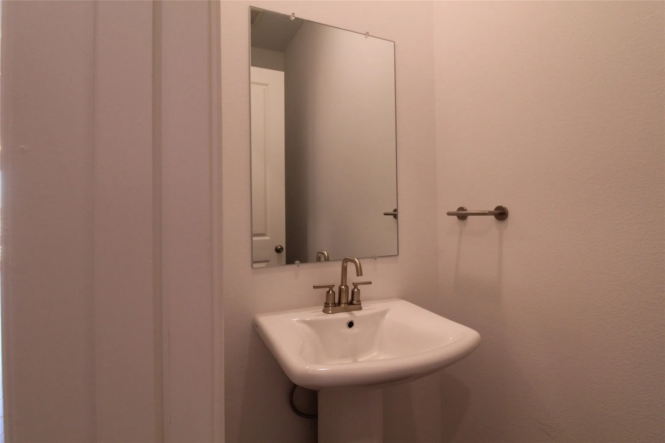 Pedestal sink with brass-finish faucet and mirror