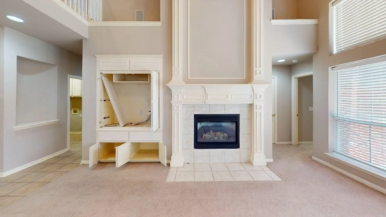 Fireplace with tile surround, built-in cabinetry, and carpet flooring