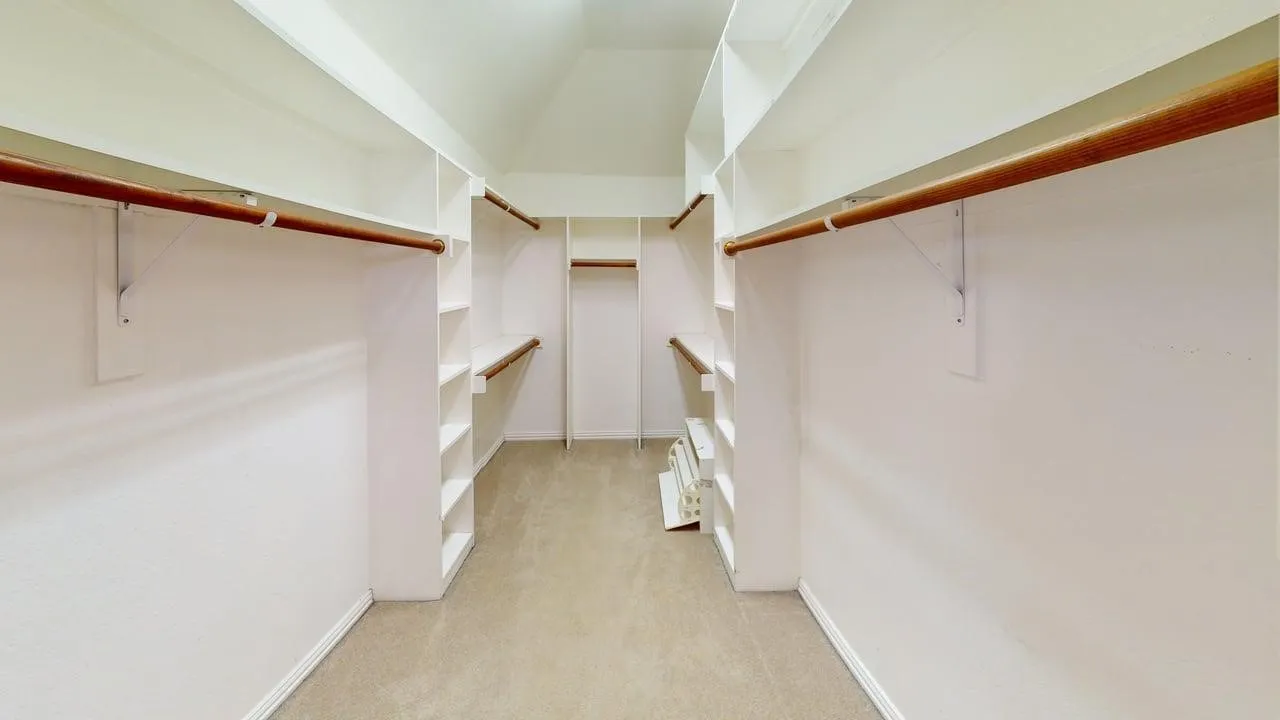 Walk-in closet featuring built-in shelving, hanging rods, and carpet flooring
