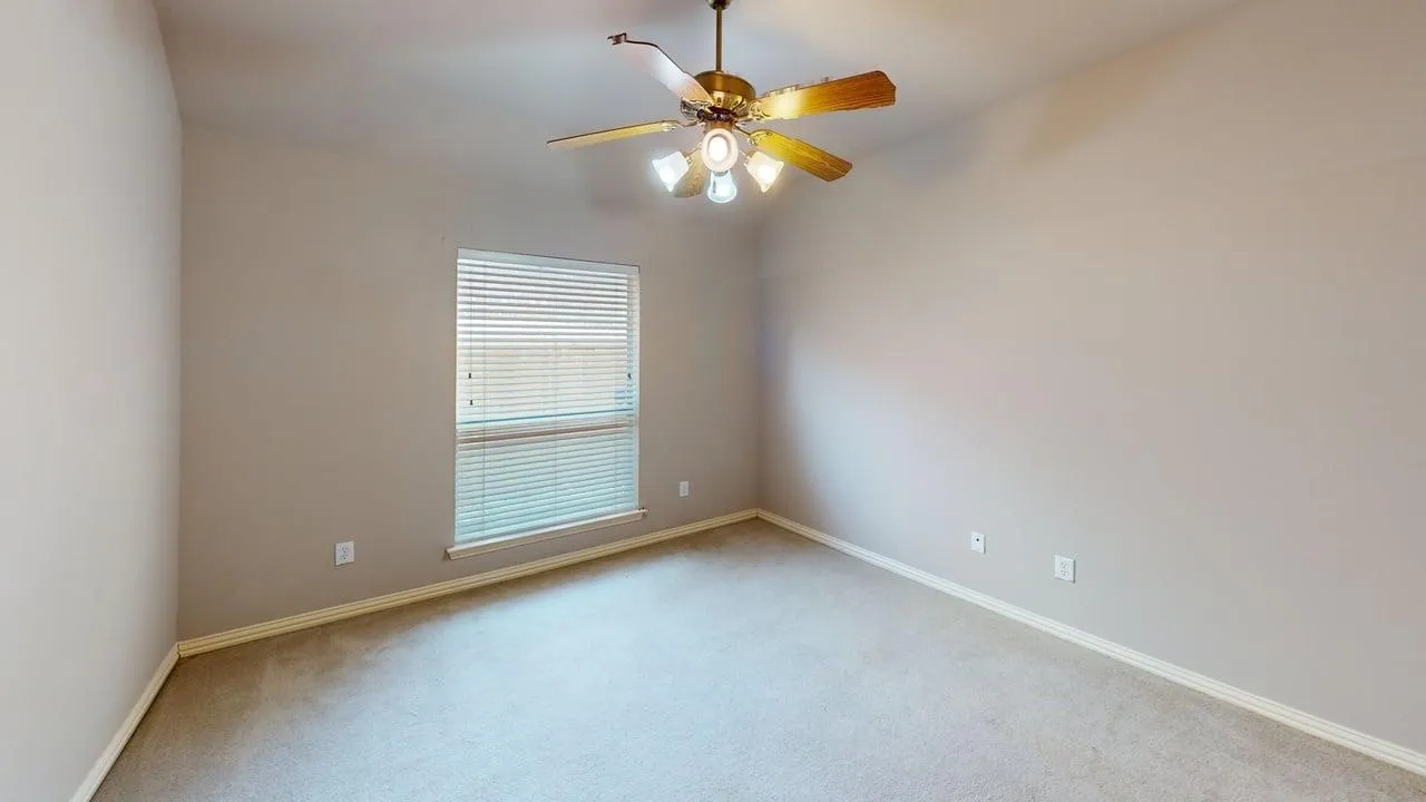 Spacious bedroom with neutral wall finishes, plush carpeting, and abundant natural light from a large window with horizontal blinds