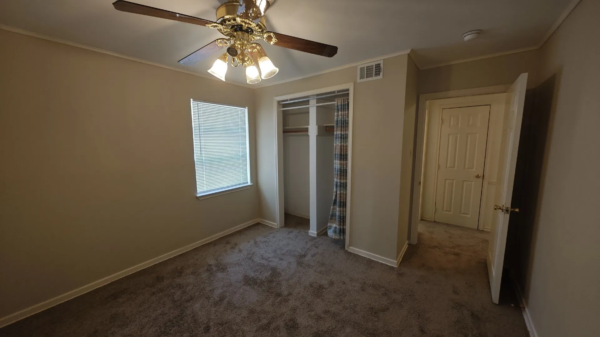Carpeted room with a ceiling fan light fixture, window with blinds, and a built-in closet with curtain