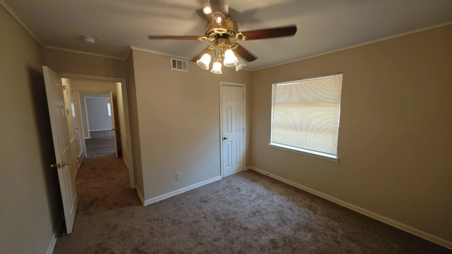 Carpeted room featuring a ceiling fan with light fixture, window with blinds, and white paneled doors