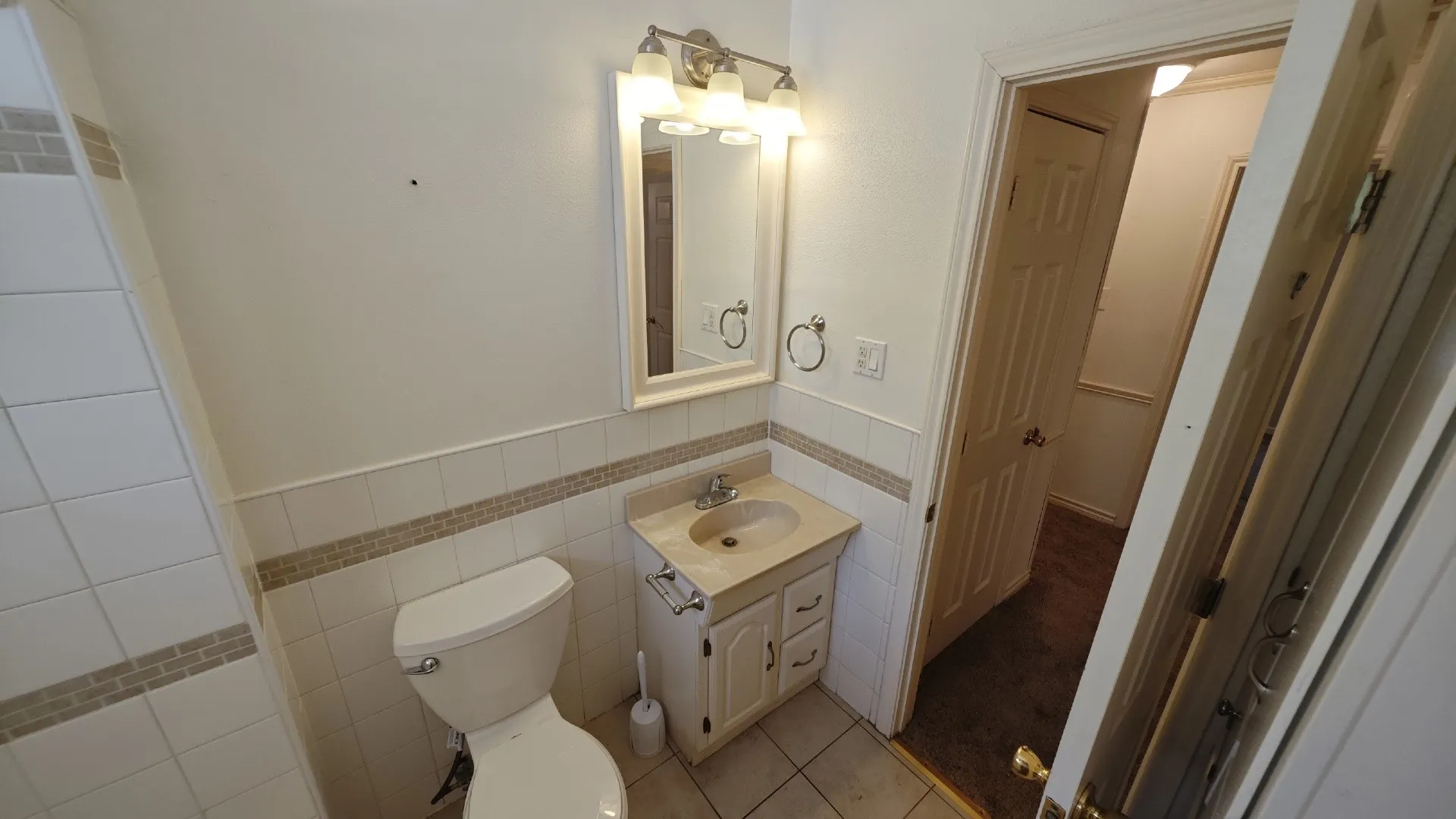 Vanity with integrated sink, wall-mounted mirror, and overhead lighting
