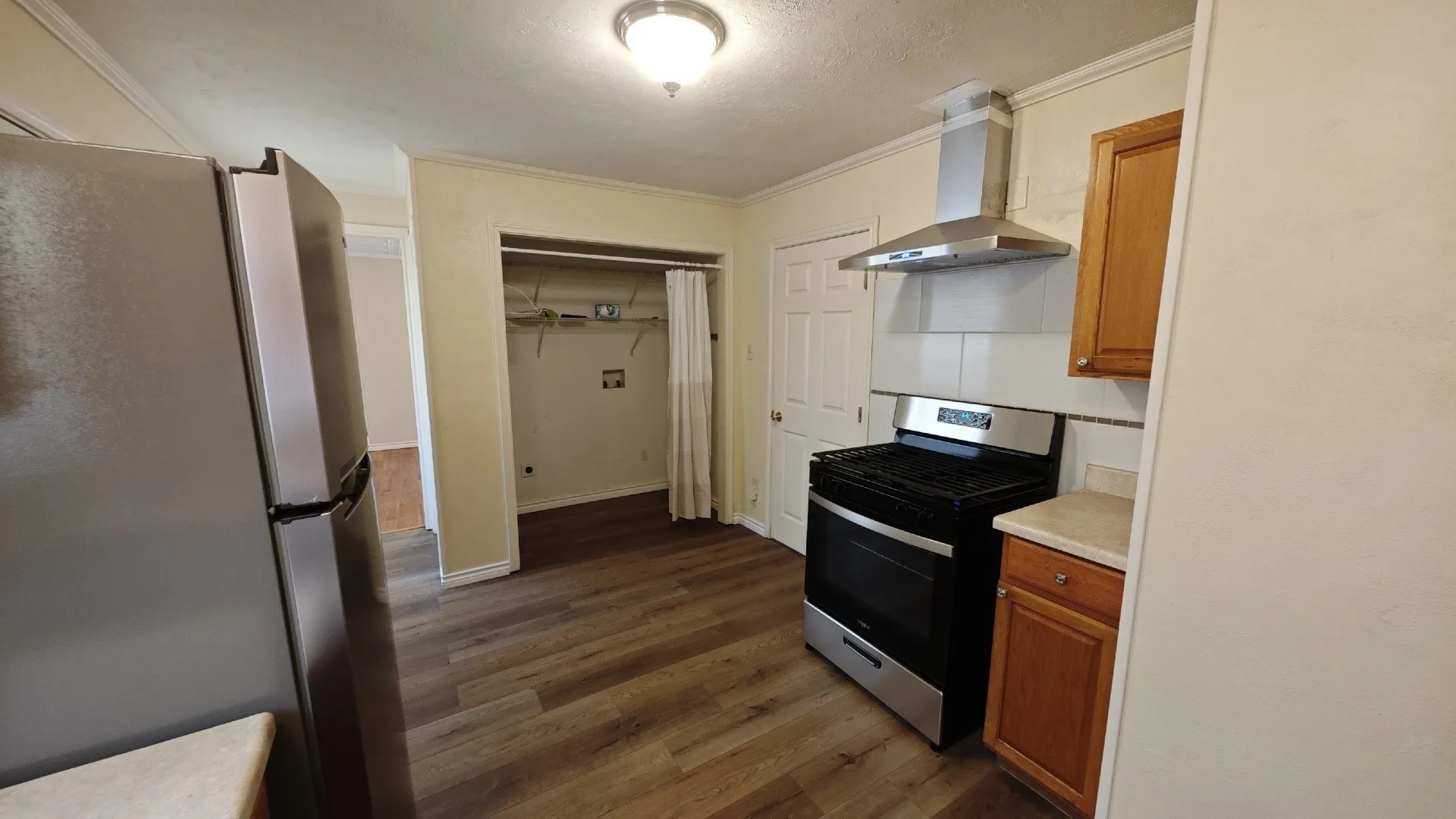 Kitchen featuring wood-finish flooring, stainless steel appliances, wood cabinetry, and a tile backsplash
