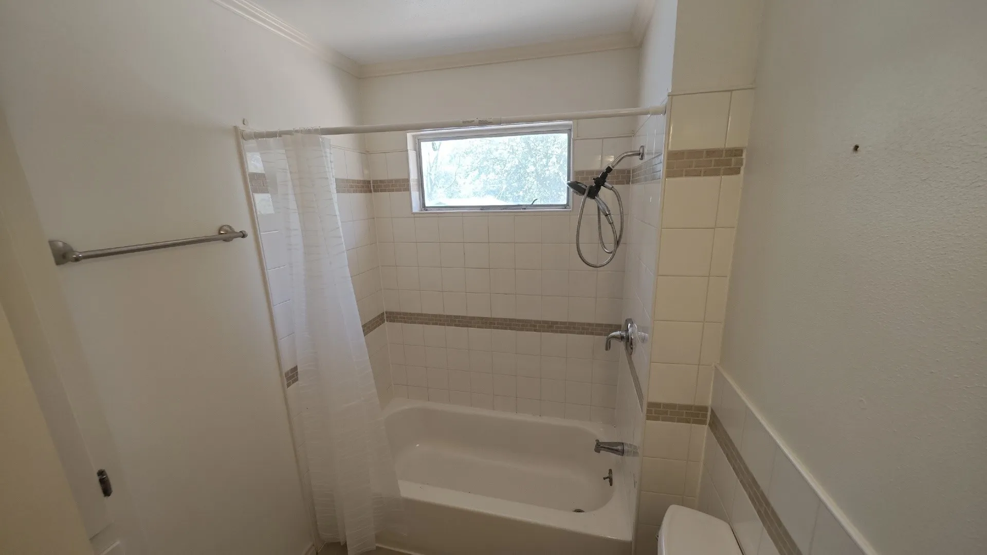 Tub and shower combination with tiled surround, decorative accent tile, and a window