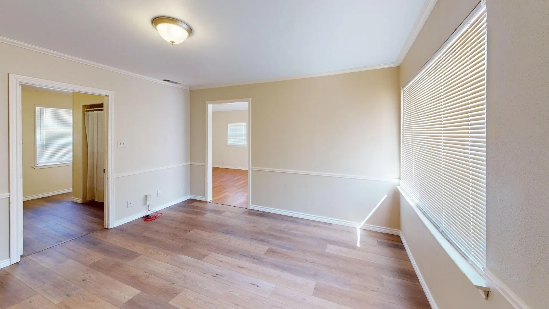 Wood-finish flooring, neutral wall tones, chair rail molding, and a flush mount ceiling light