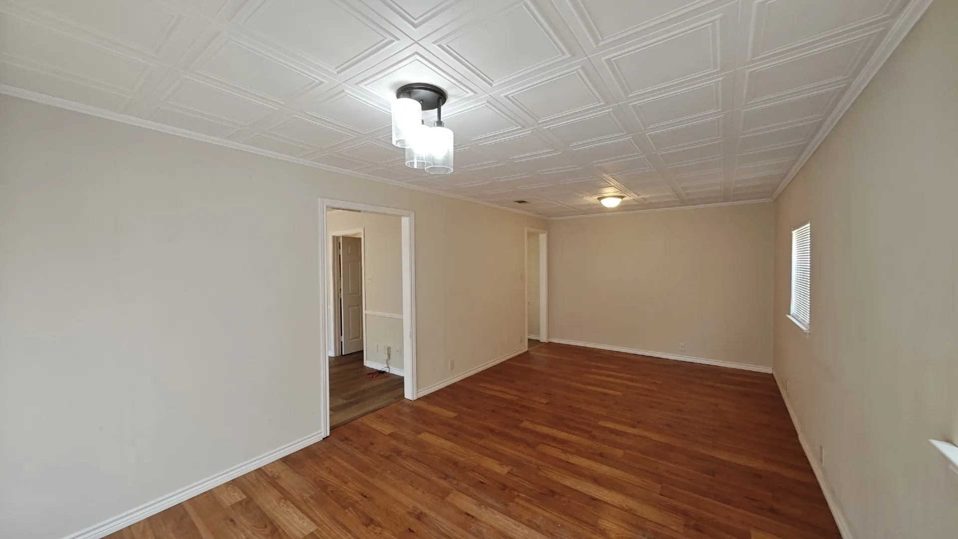 Coffered ceiling with a modern light fixture, wood-finish flooring, and neutral wall tones