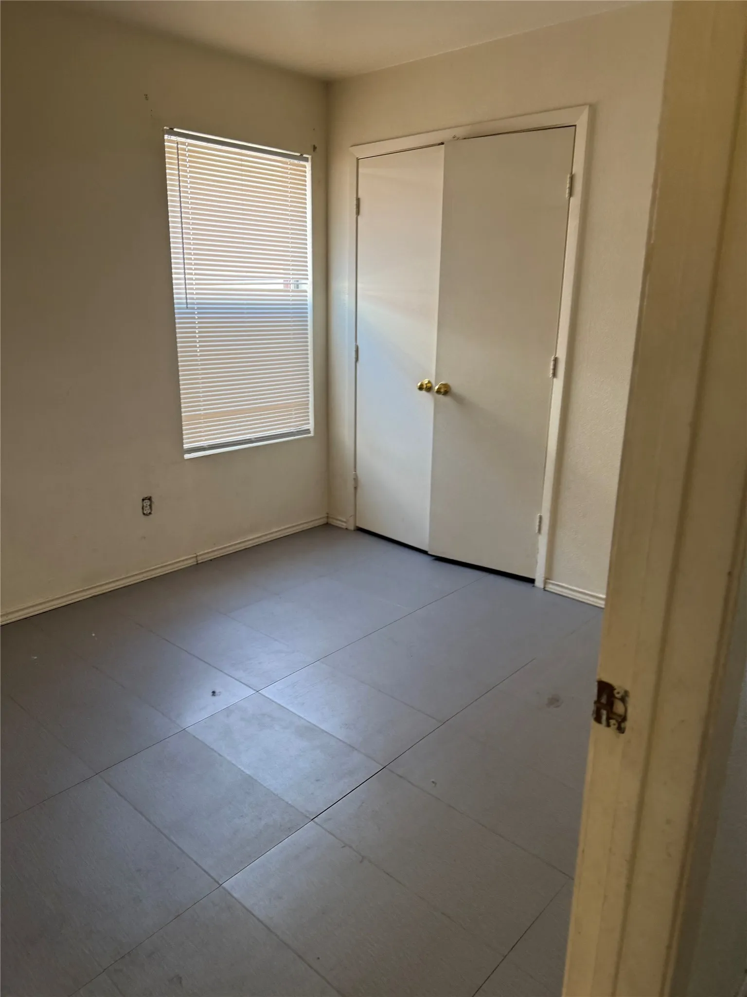 Unit B - Bedroom 1 - Room featuring a window with horizontal blinds and a dual-door closet with brass hardware