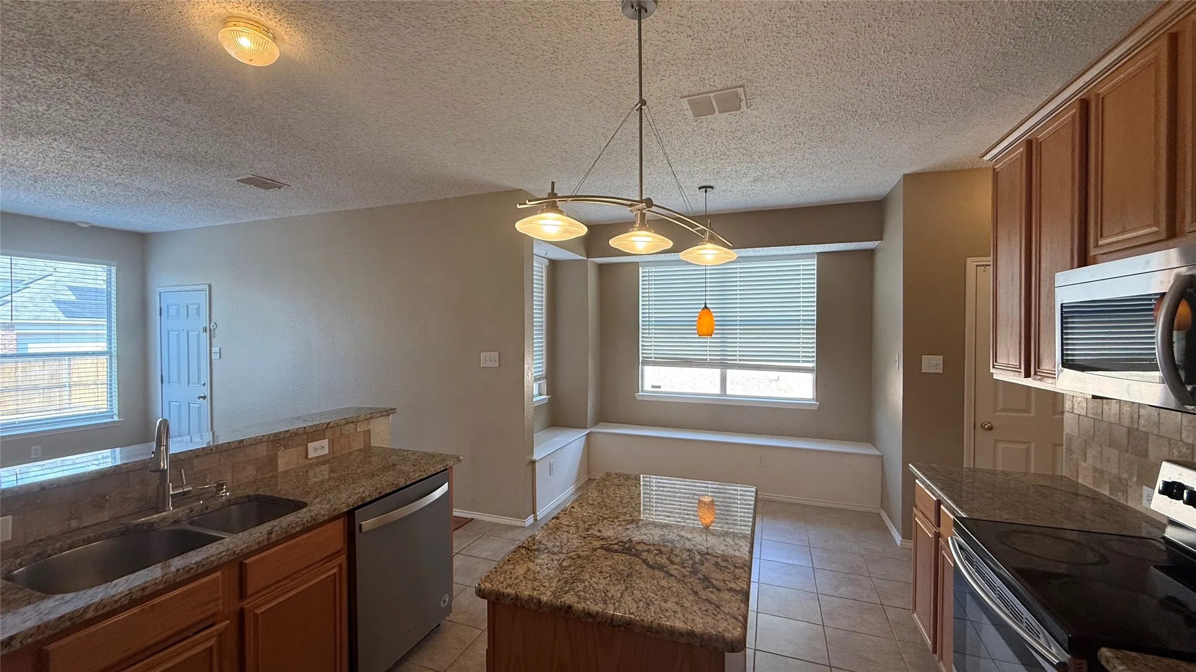 Kitchen featuring a double basin sink, stainless steel dishwasher, built-in microwave, and a breakfast bar with granite countertops